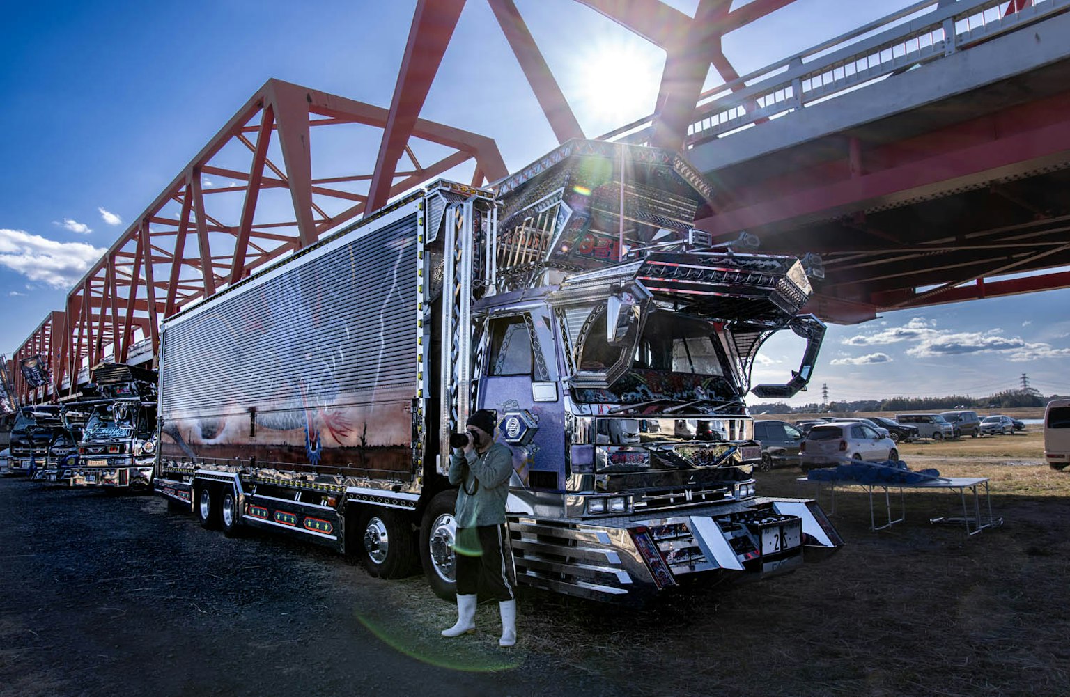 Camion parcheggiato sotto un ponte rosso con un autista