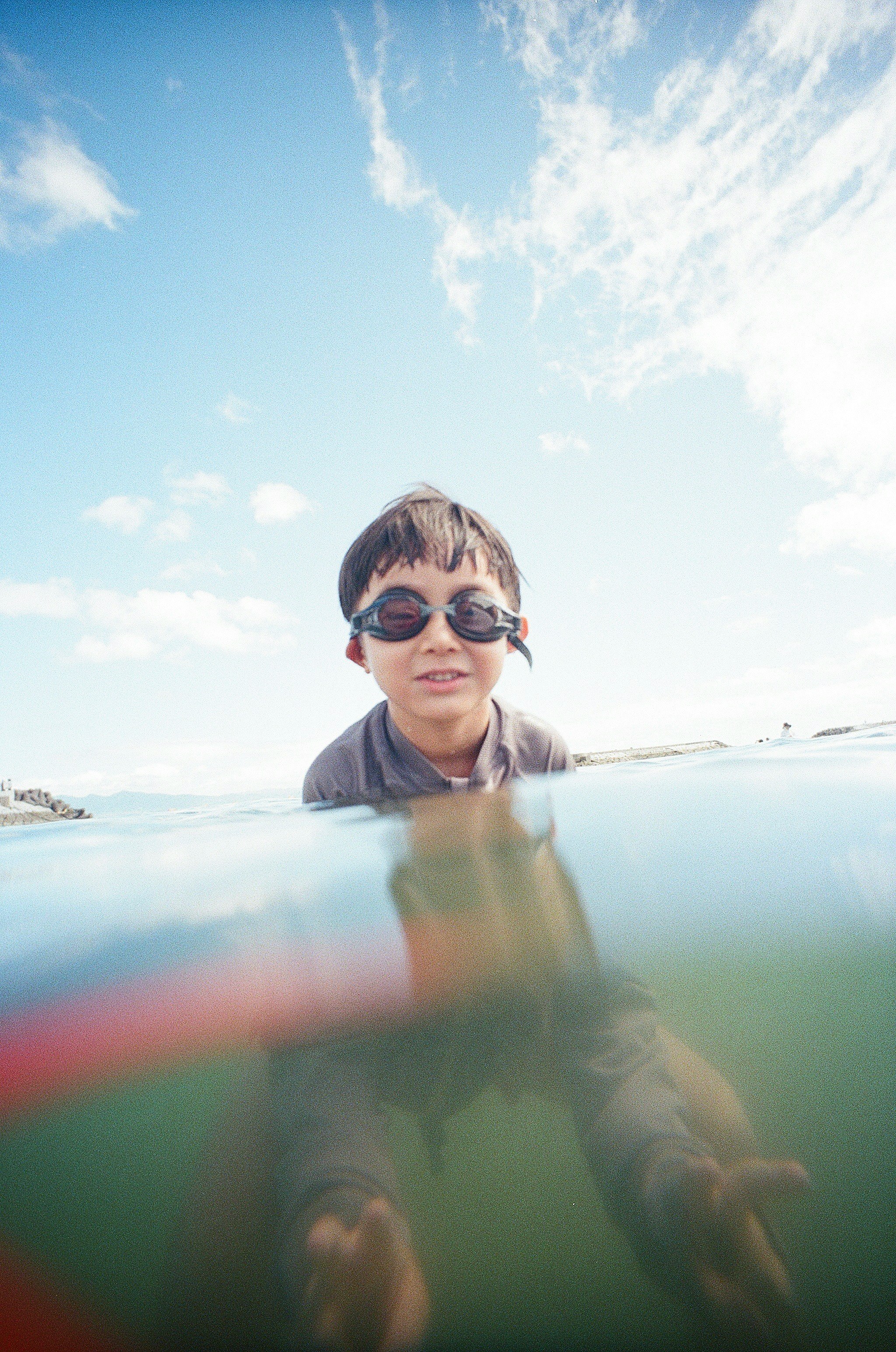 海辺で笑顔の子どもが水面から顔を出す夏の一枚