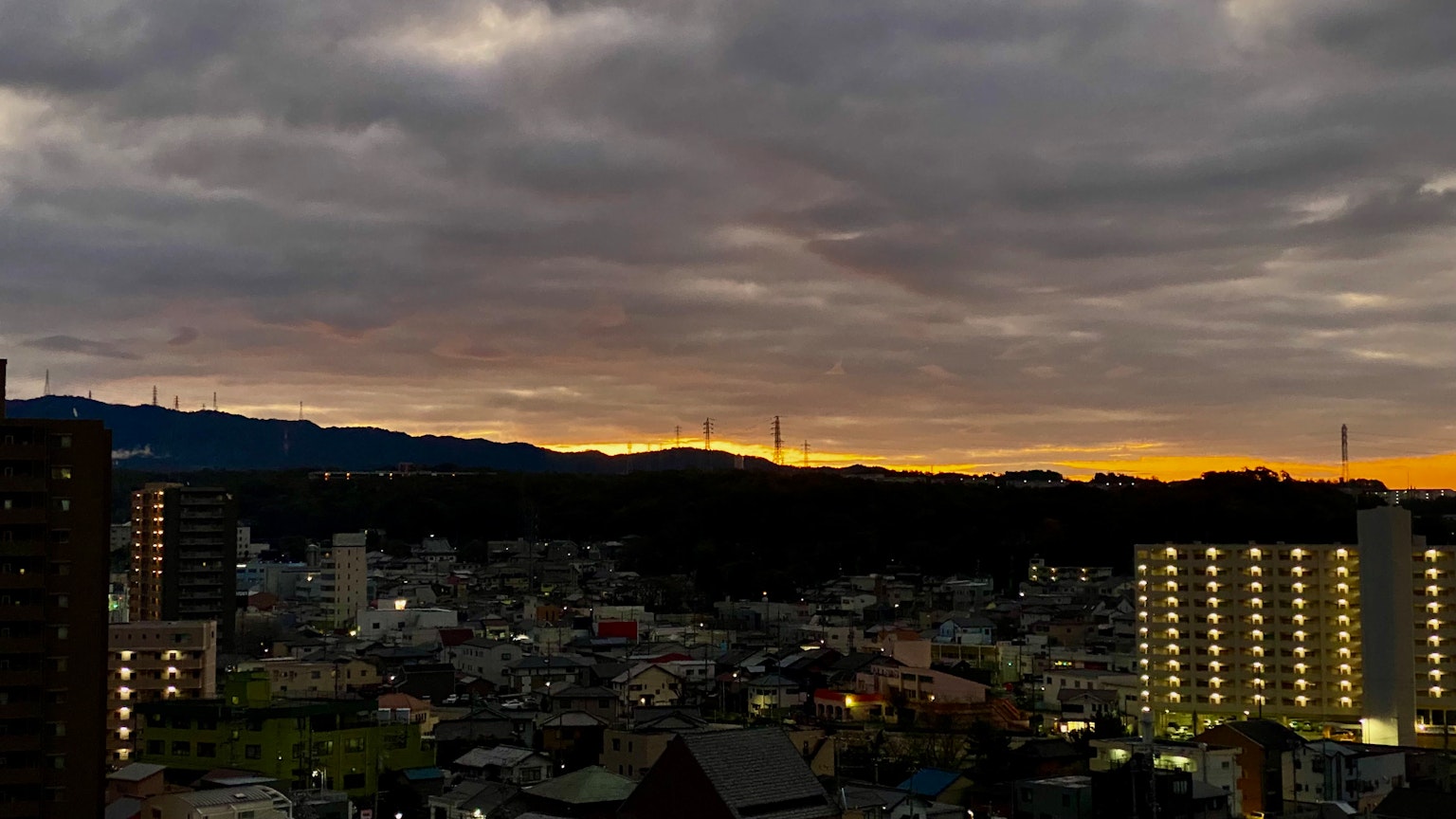 Paisaje urbano al anochecer con un cielo de atardecer edificios altos y casas visibles