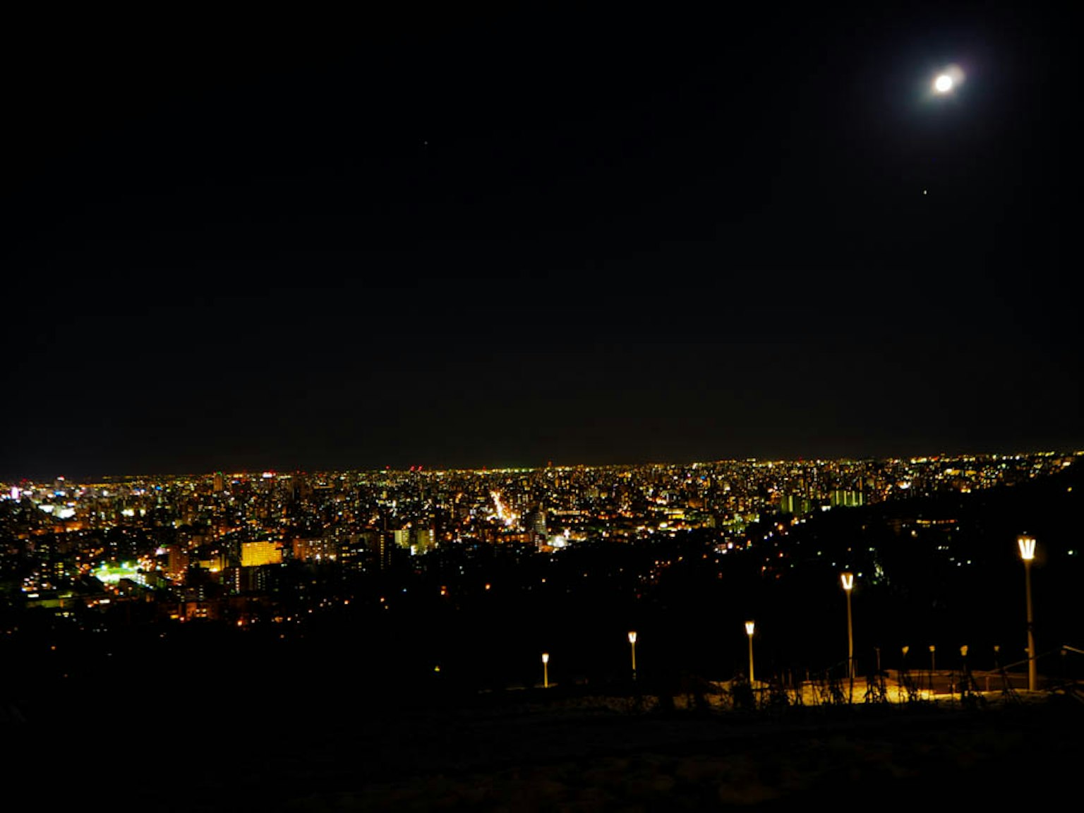 Vast city skyline illuminated at night with bright lights and a clear sky