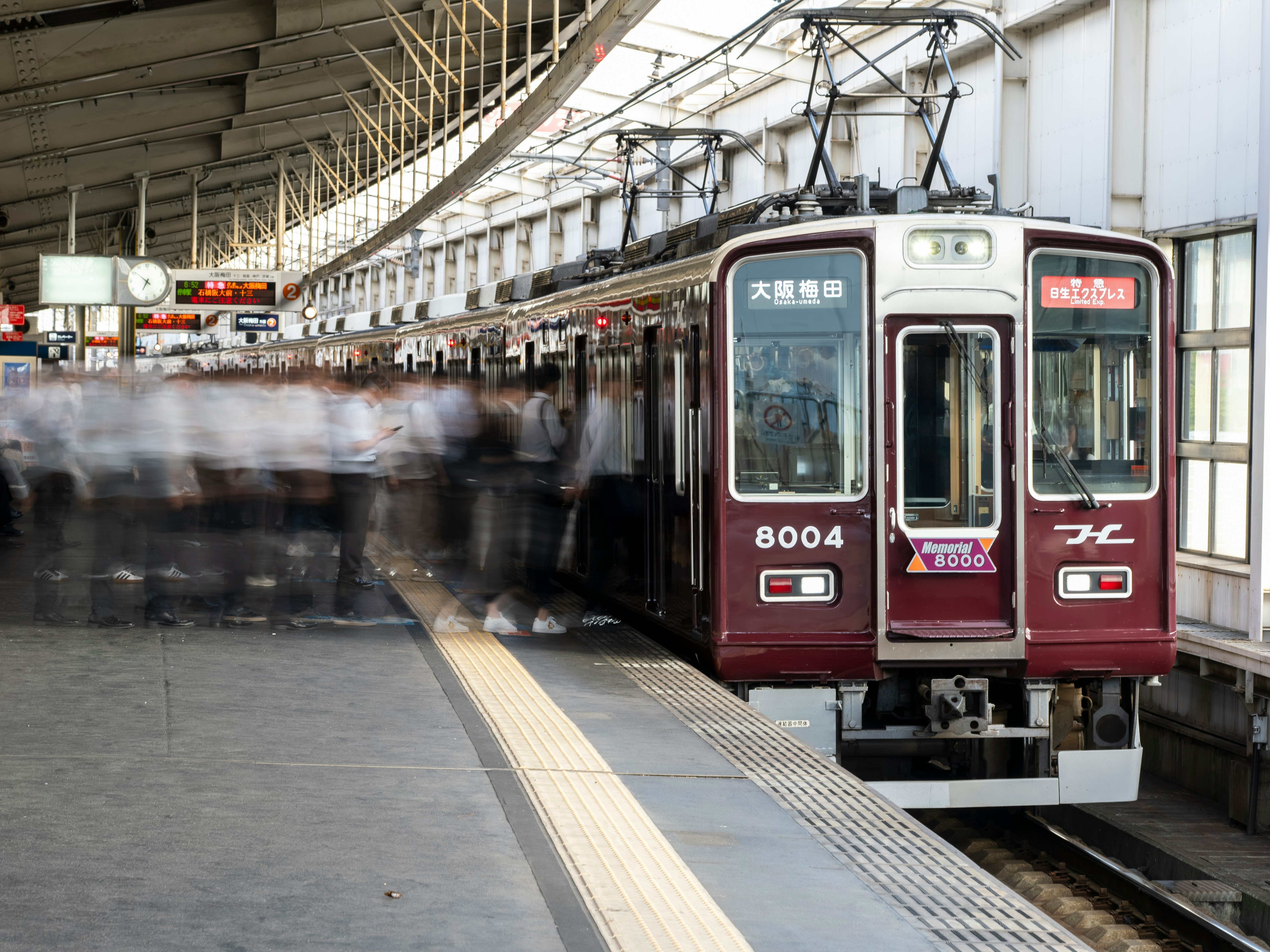 朝の通勤ラッシュの駅ホームで並ぶ阪急電車