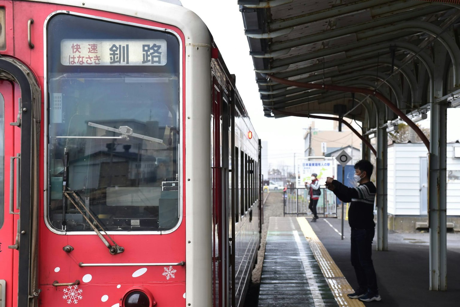 รถไฟแดงที่สถานีมีคนยืนอยู่บนชานชาลา