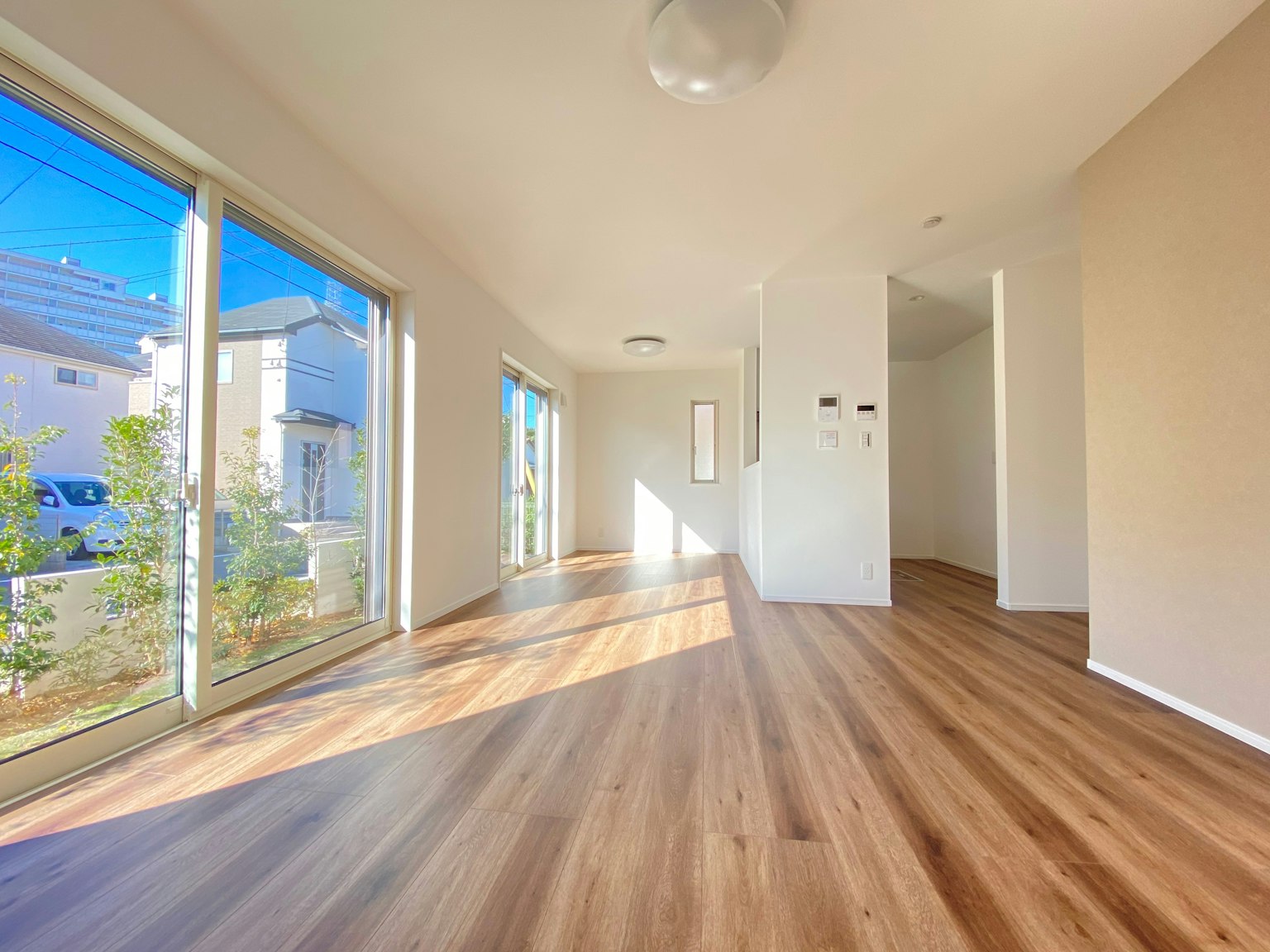 Geräumiges Wohnzimmer mit hellem Holzboden und natürlichem Licht, das durch die Fenster strömt
