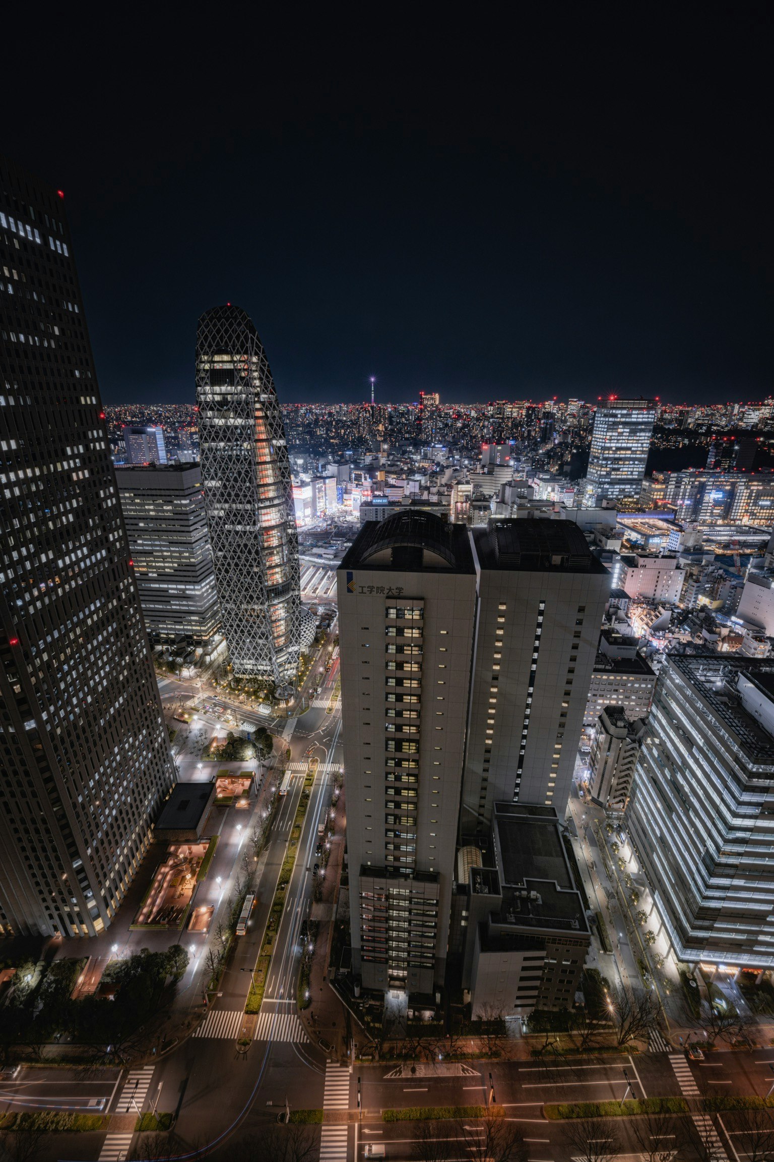 Vista notturna di uno skyline urbano con grattacieli illuminati e strade affollate