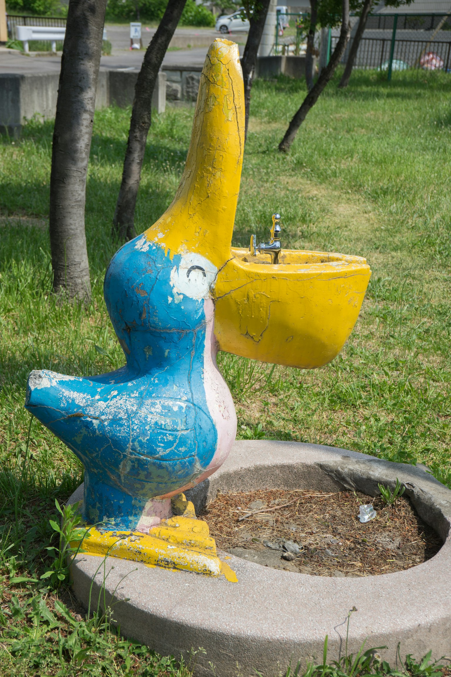 Sculpture de pélican coloré bleu et jaune servant de fontaine