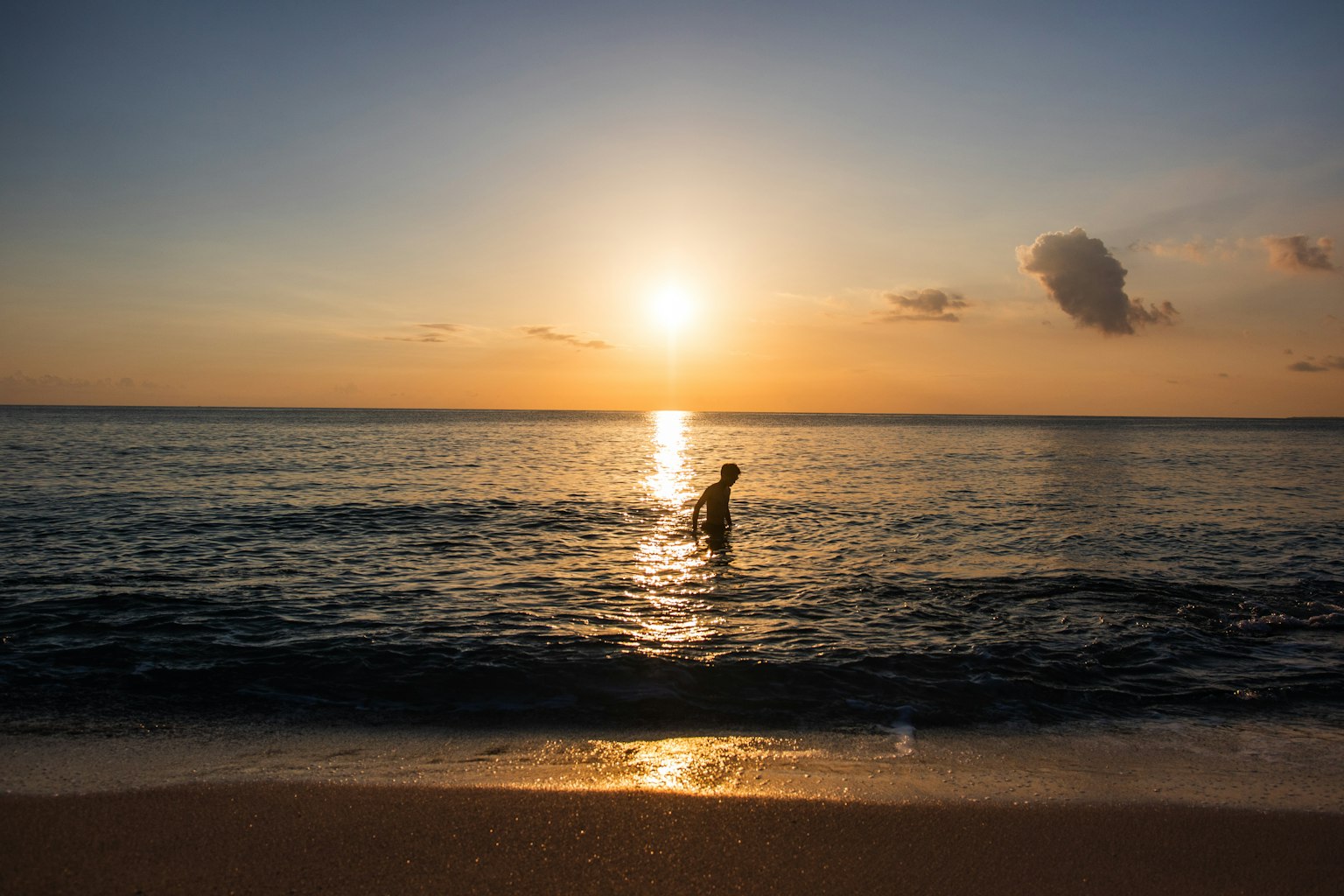 Una persona che si immerge nel mare con un tramonto sullo sfondo