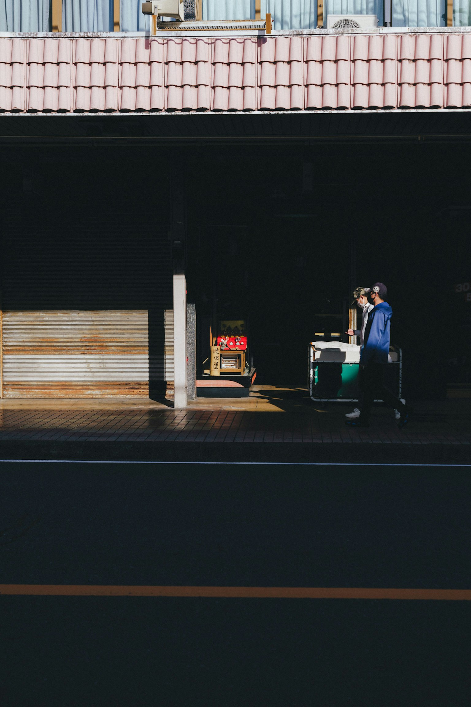 暗い場所で荷物を運ぶ人とカートが見える