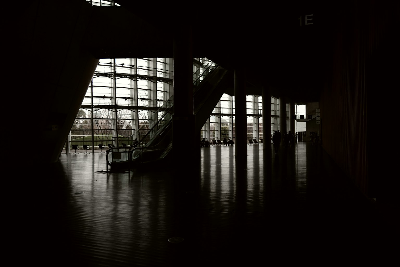 Dark interior featuring large windows and stairs with reflective floor