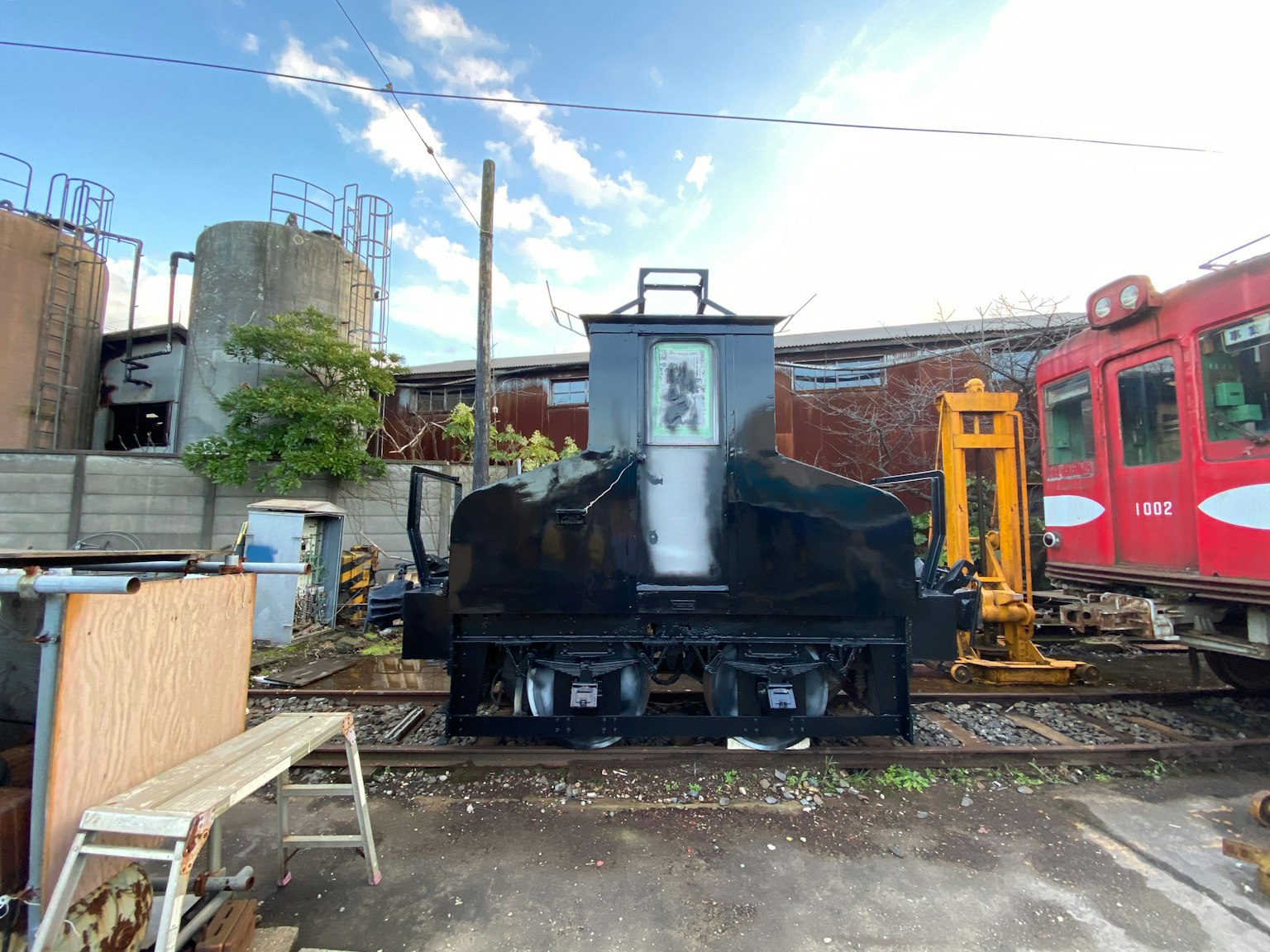 รถจักรสีดำบนรางรถไฟพร้อมภูมิทัศน์อุตสาหกรรมและท้องฟ้าสีฟ้า