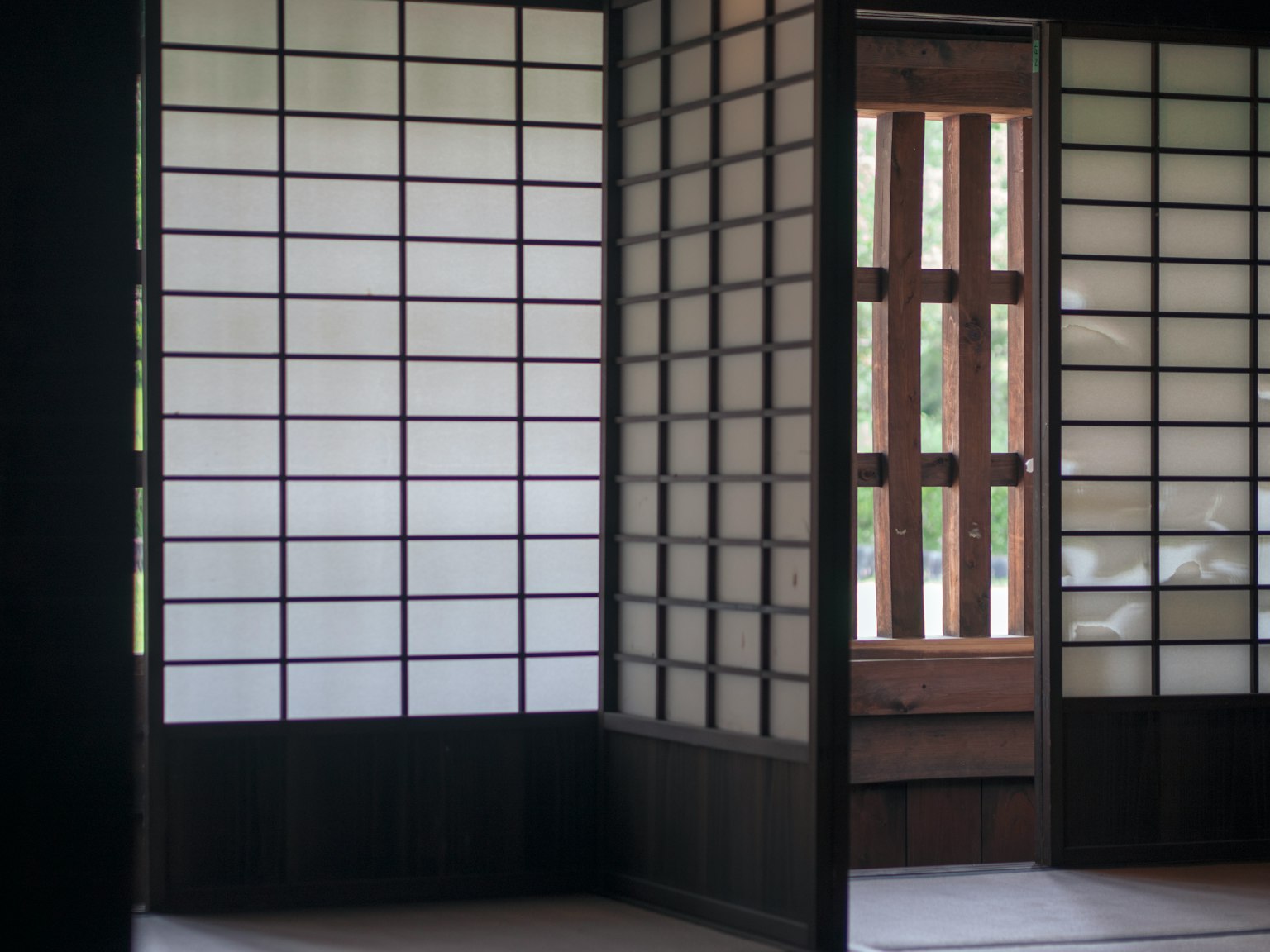 A serene space featuring wooden shoji screens and a part of a traditional Japanese room