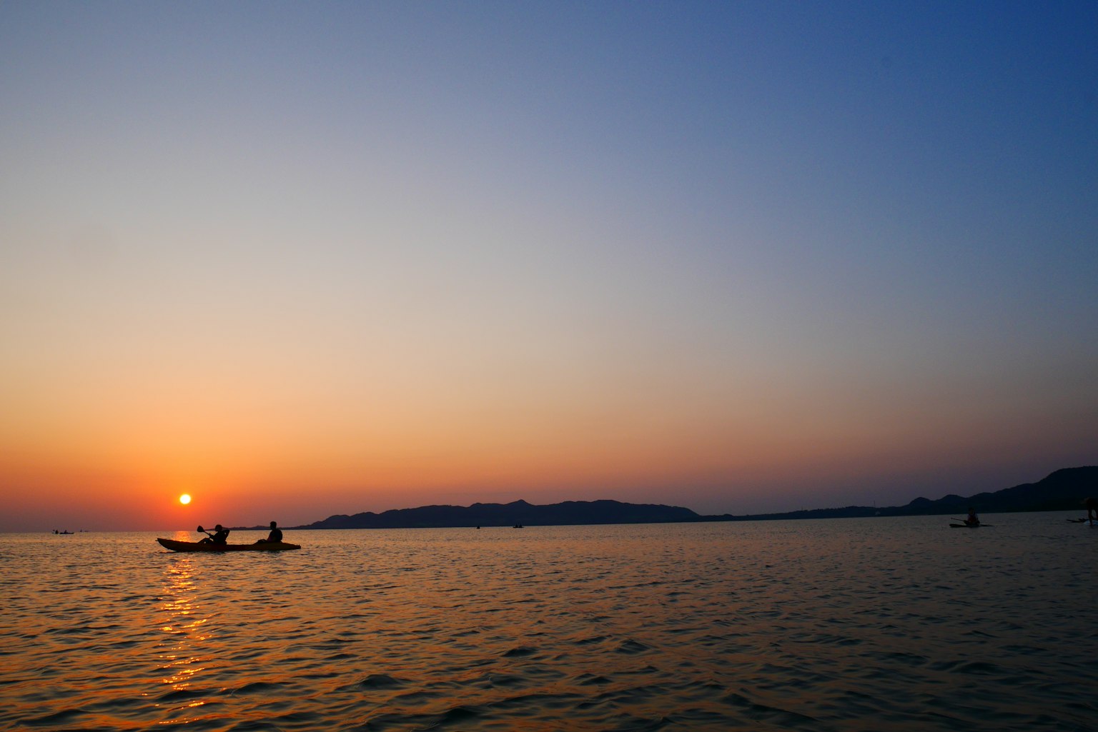 Scenic view of small boats on the ocean during sunset