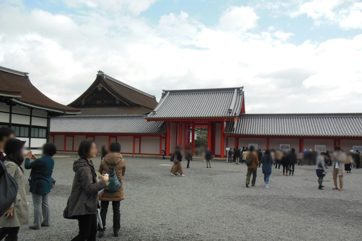 Tourists exploring a traditional Japanese temple exterior featuring a red gate and historical buildings