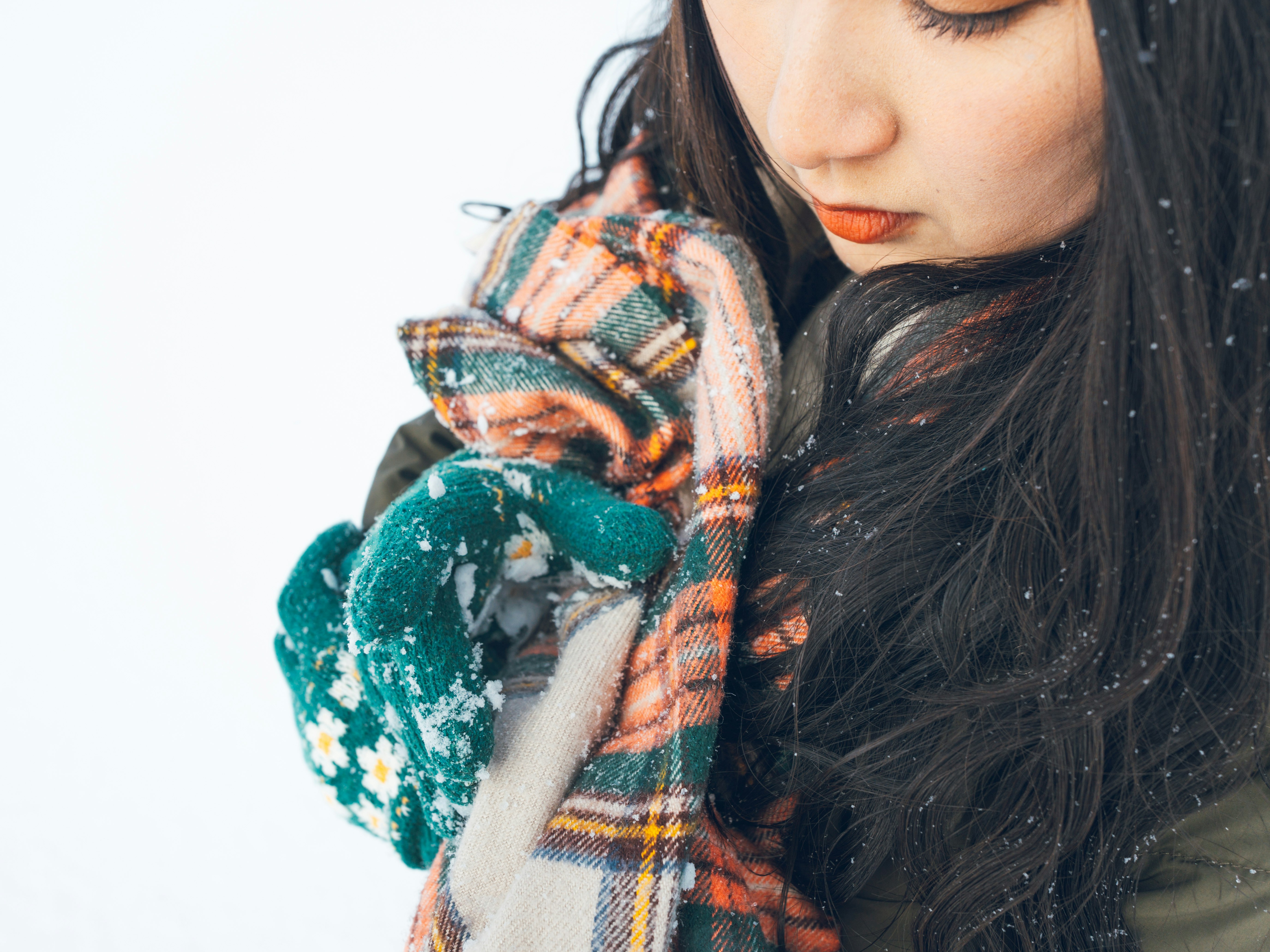雪の中でマフラーを巻く女性