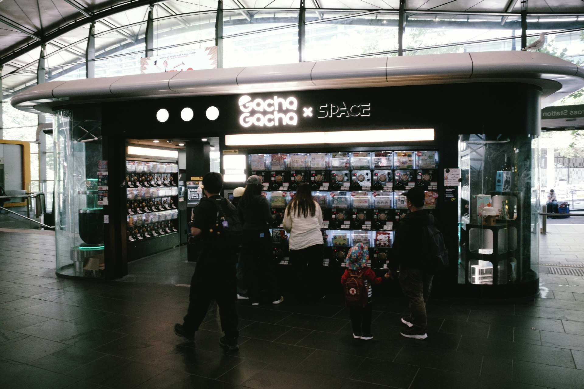 駅構内のガチャガチャ筐体が並ぶ売店前の通路