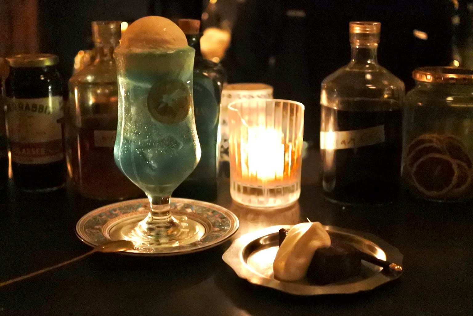 Một ly cocktail xanh với một viên kem được phục vụ trên đĩa bên cạnh