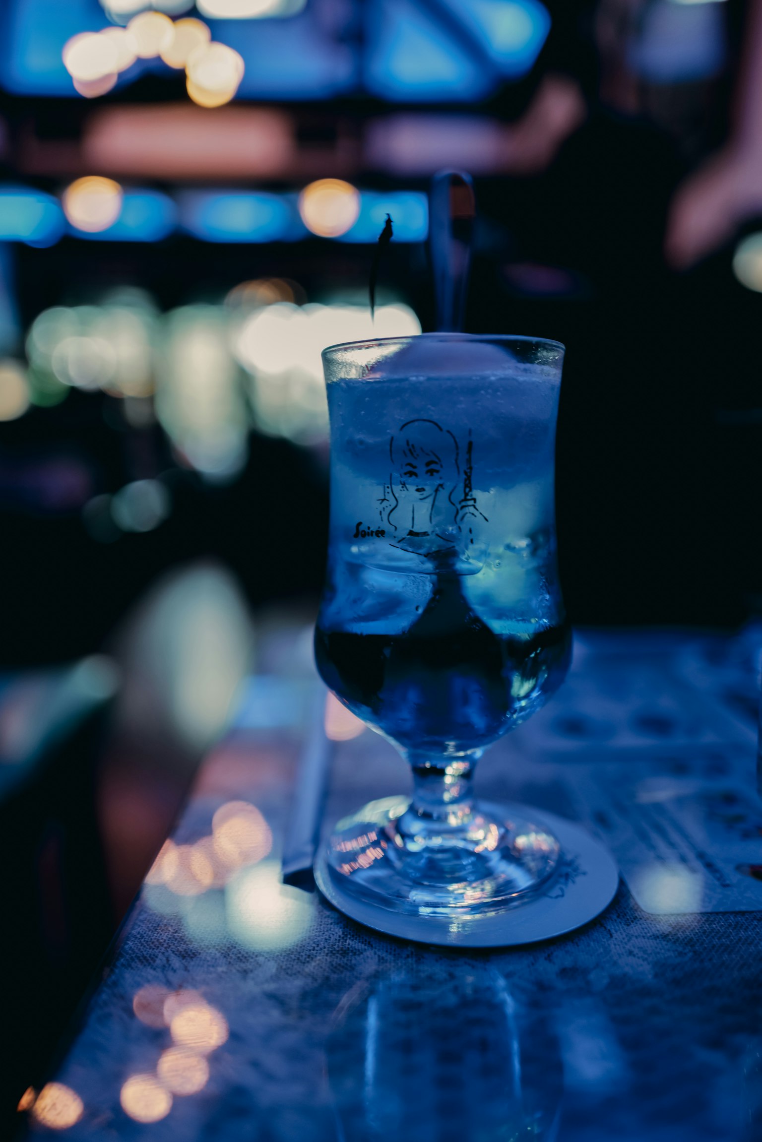 Blauer Cocktail in einem Glas auf einem Bartisch bei Nacht
