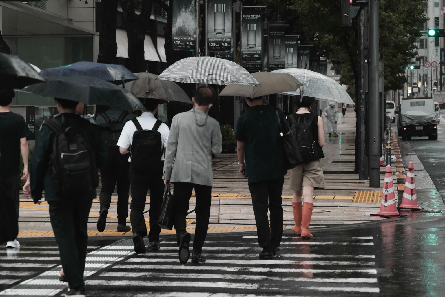 Menschen mit Regenschirmen über einen Zebrastreifen bei Regen gehen