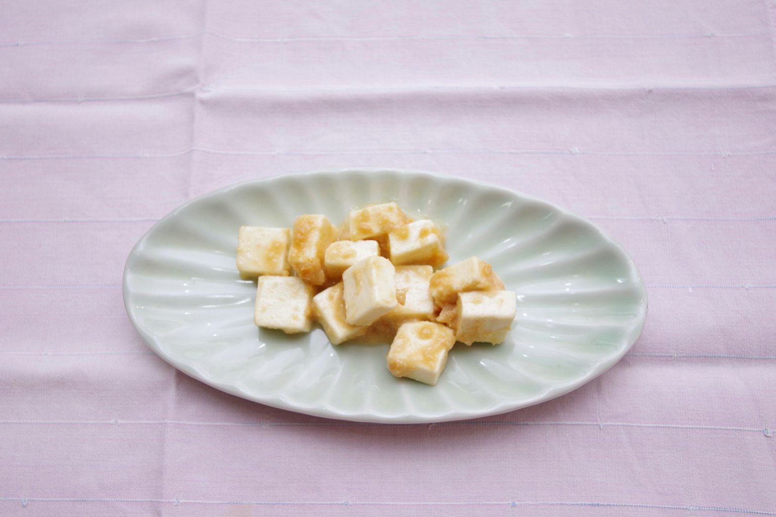 Cubes de tofu blanc disposés sur une assiette verte claire