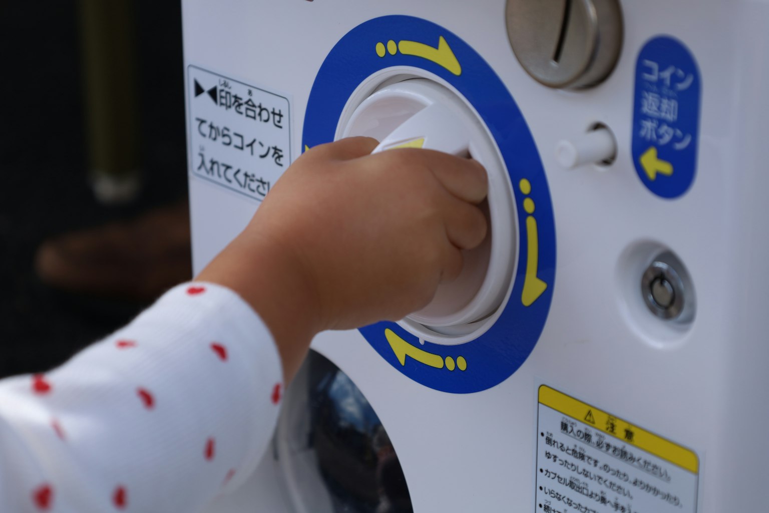 Eine Kinderhand, die eine Münzschlitz erreicht