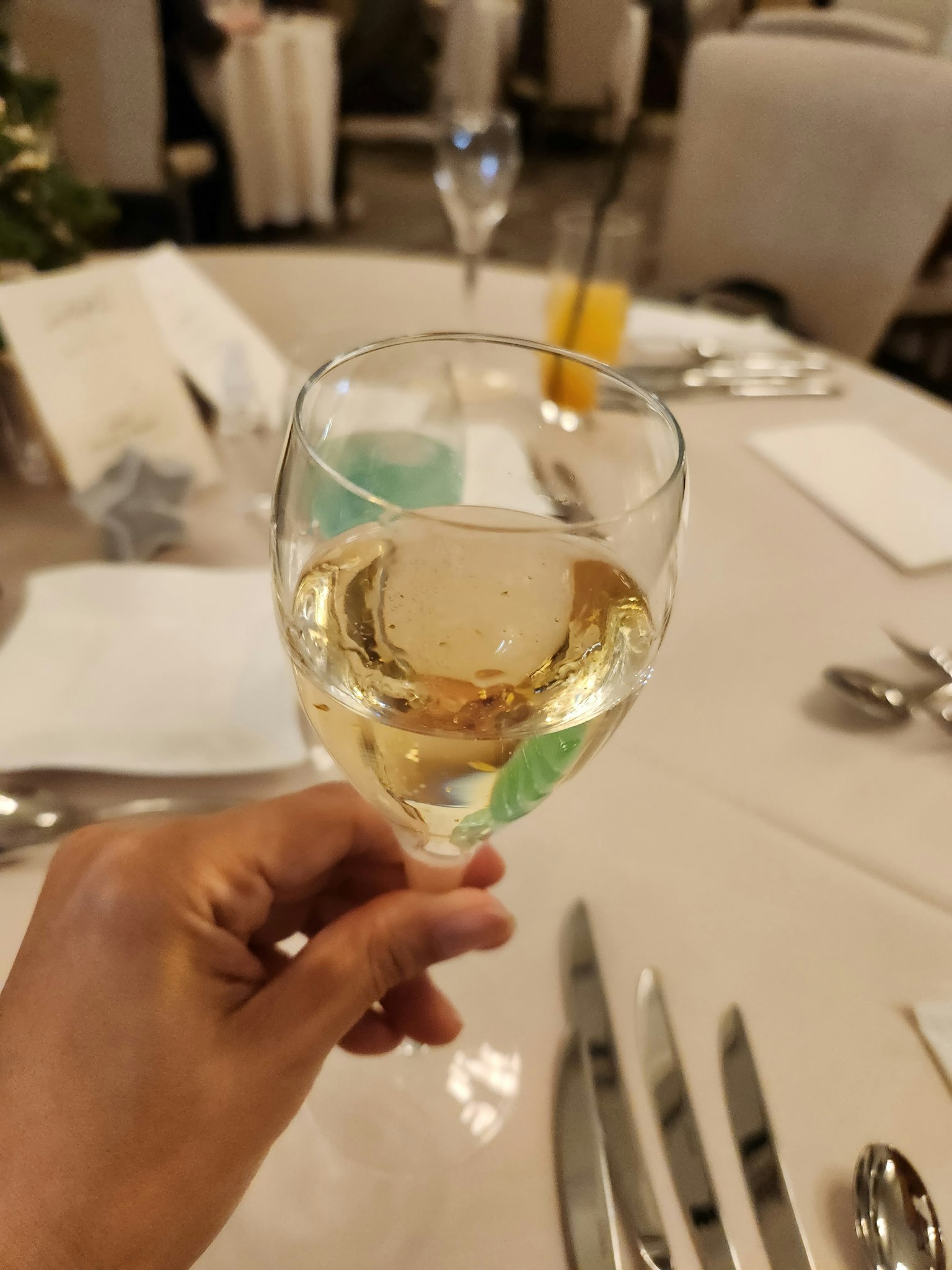 手持白葡萄酒杯优雅餐厅桌设置有餐具和餐巾