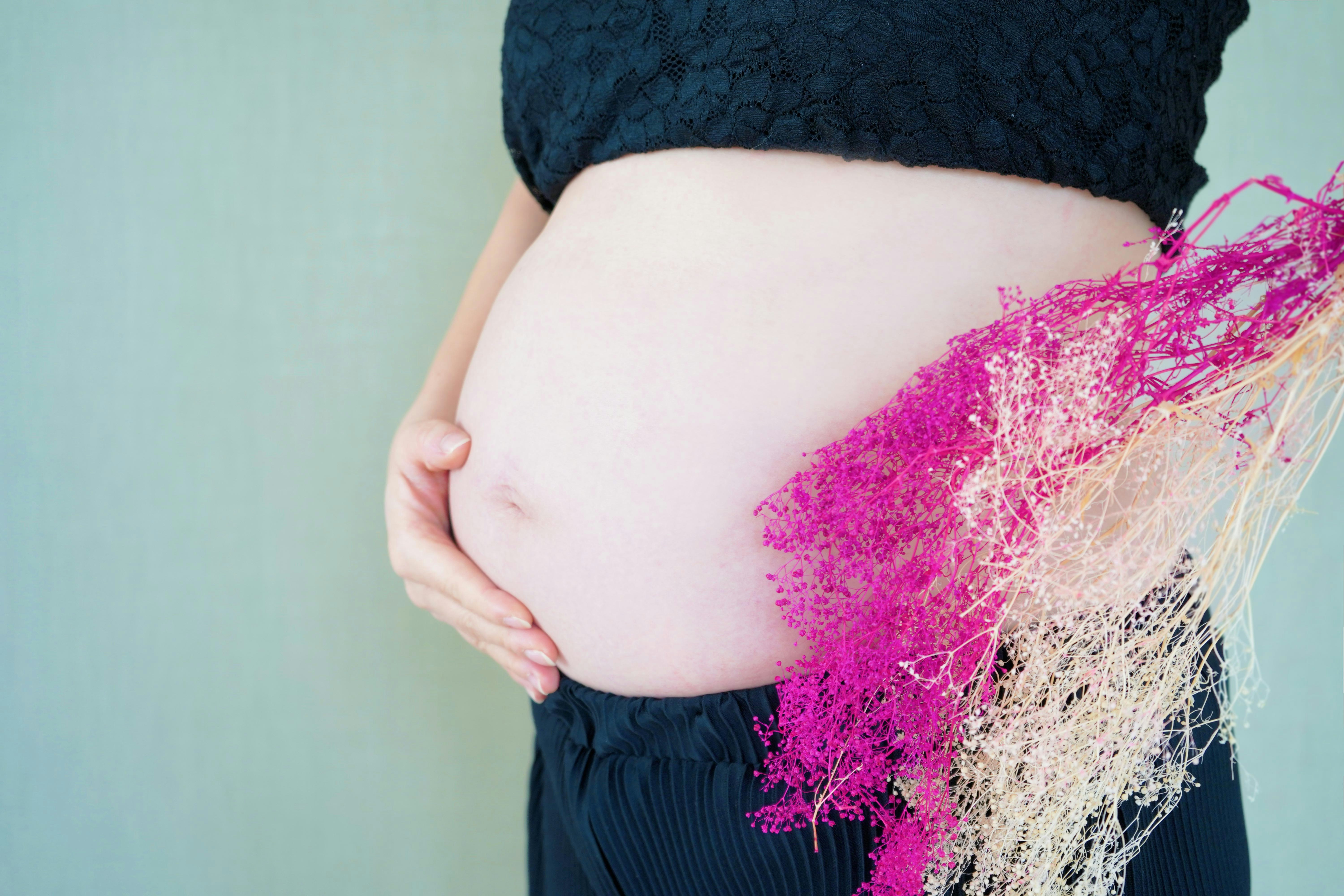 妊娠中の女性の腹部に手を添えるポーズ