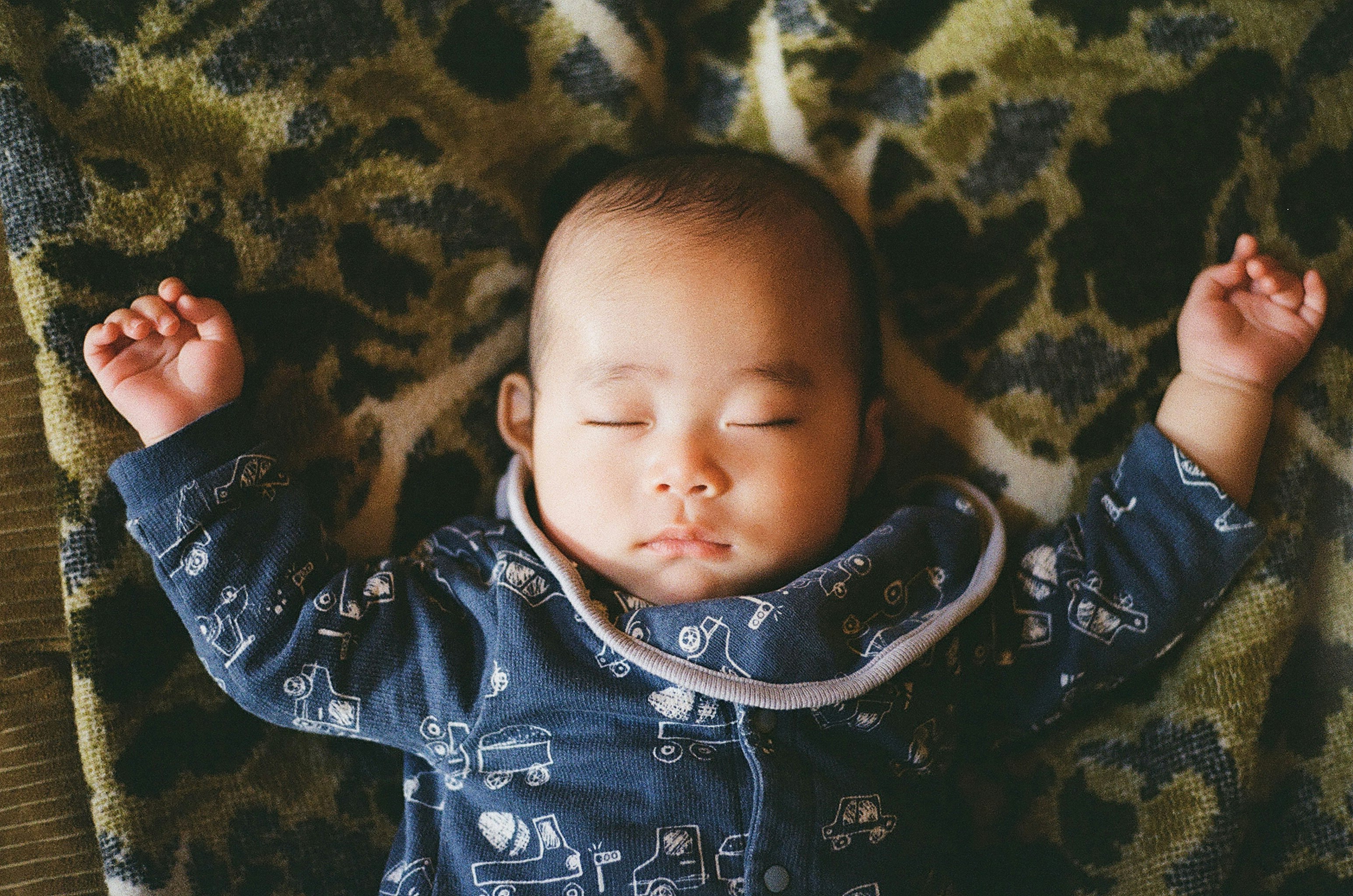 豹紋毯上張開雙臂躺著的嬰兒