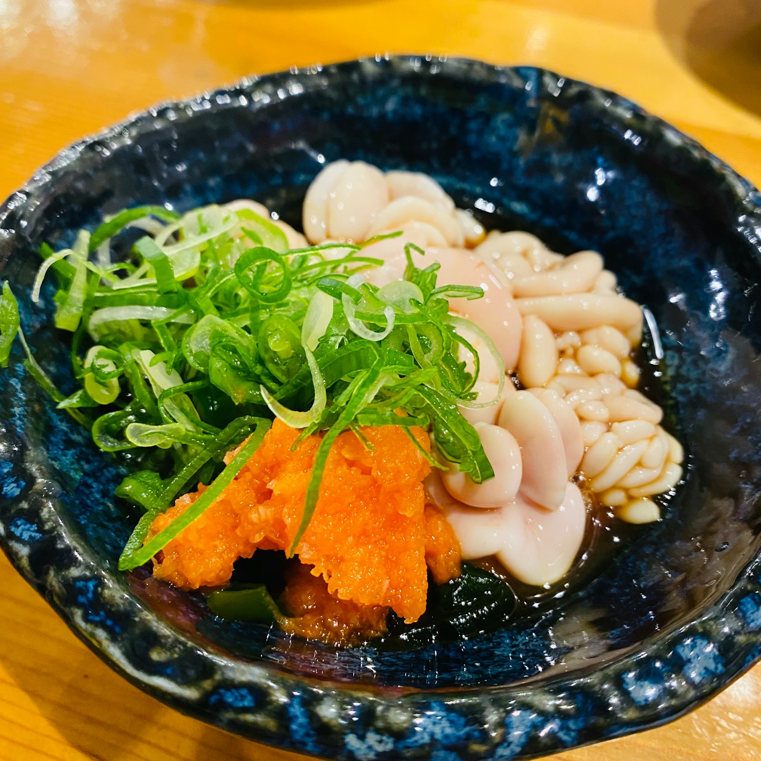 Sashimi fresco servito su un piatto blu con cipolle verdi affettate
