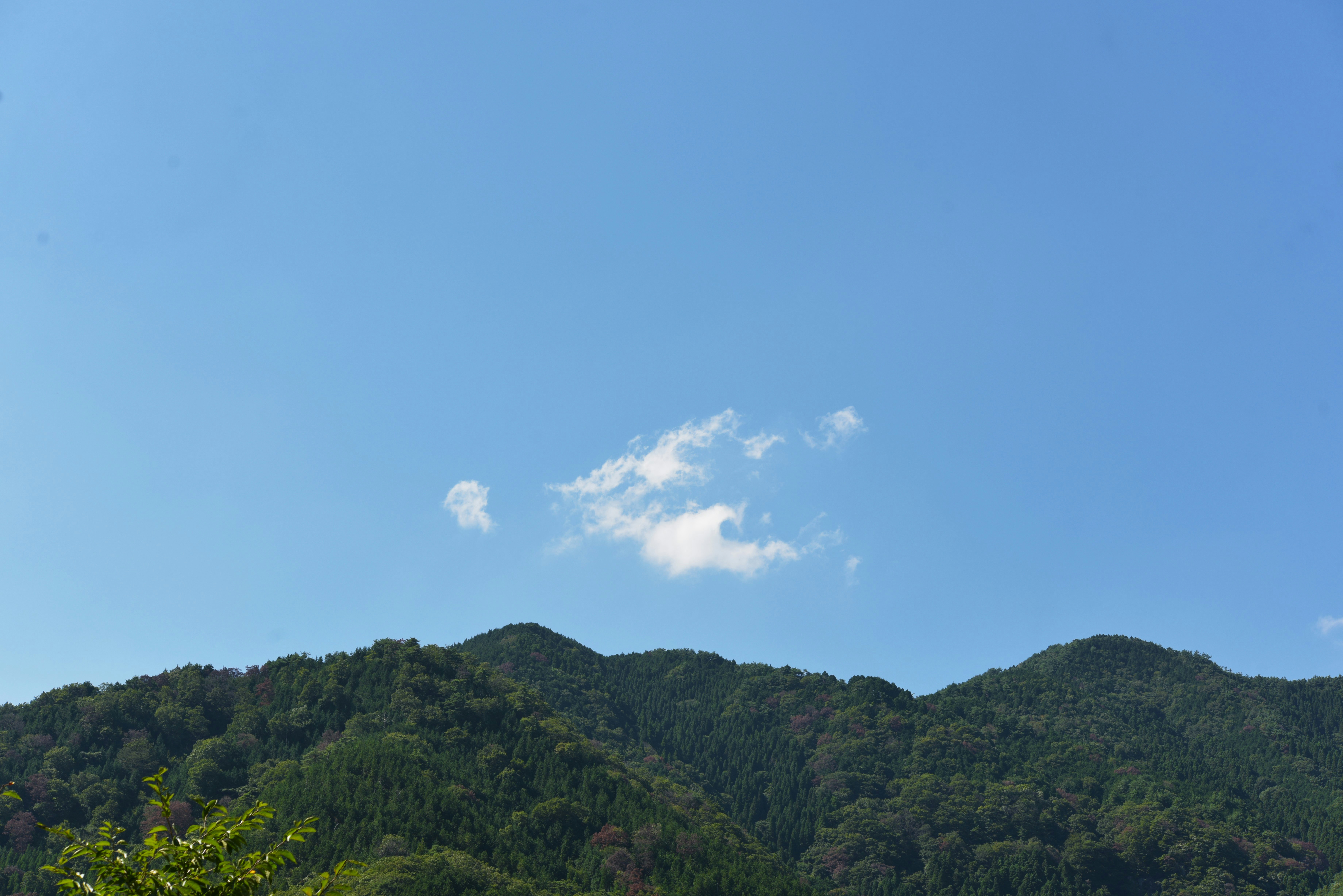 Cordilleras verdes bajo un cielo azul con nubes