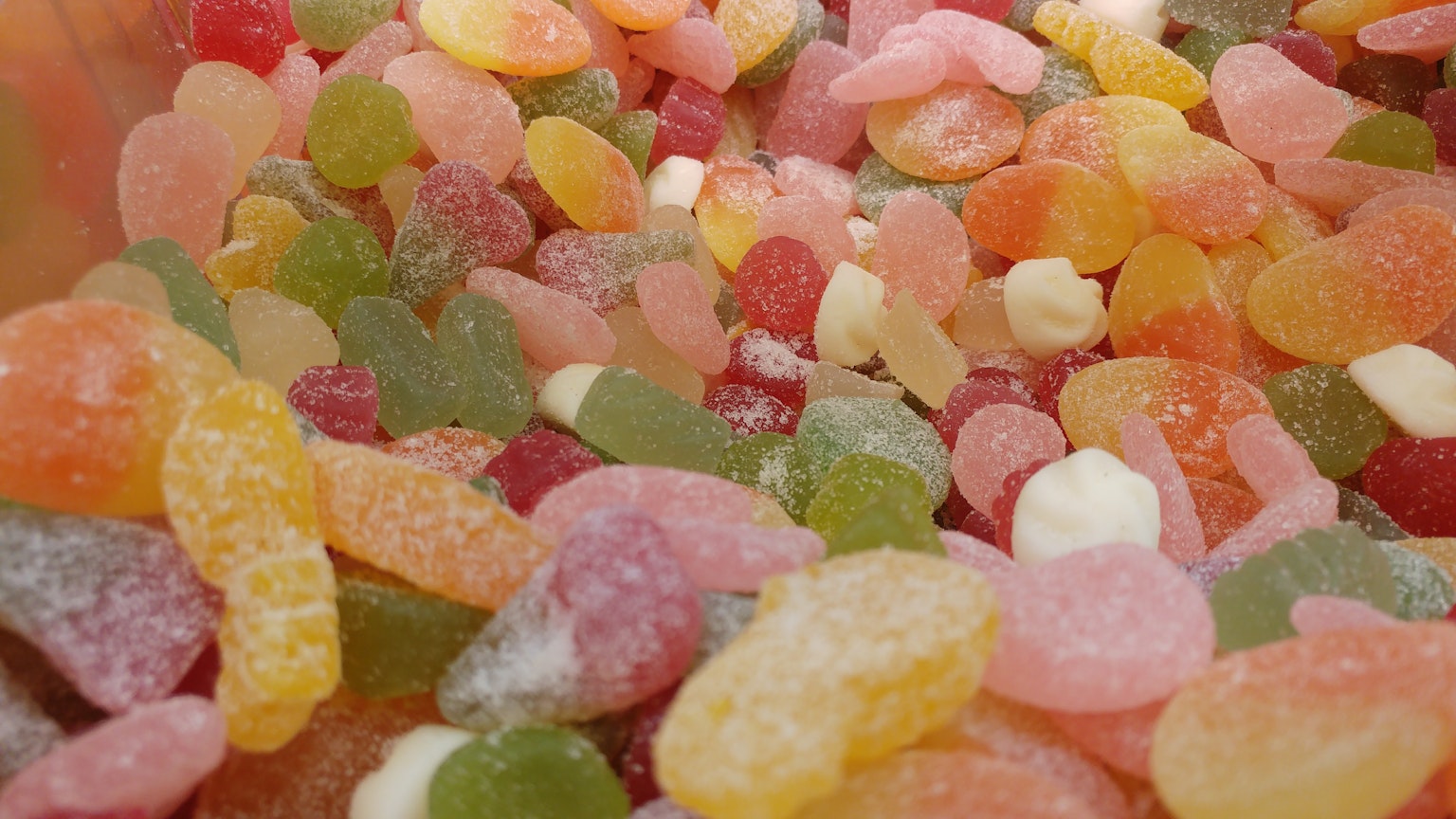 Des bonbons gélifiés colorés entassés dans un récipient transparent