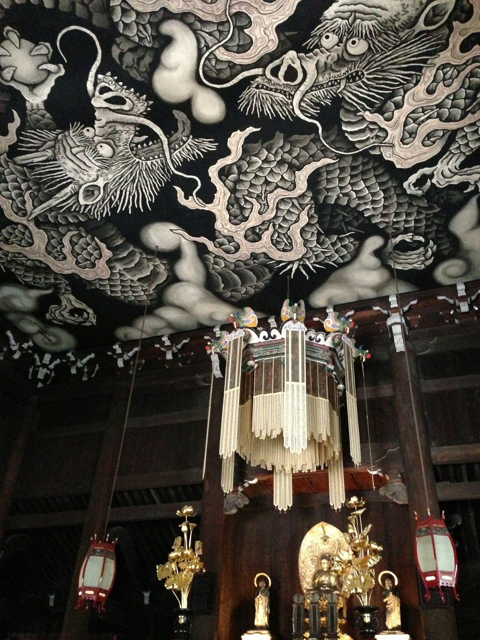 Ceiling adorned with black dragon and cloud designs featuring a central hanging ornament