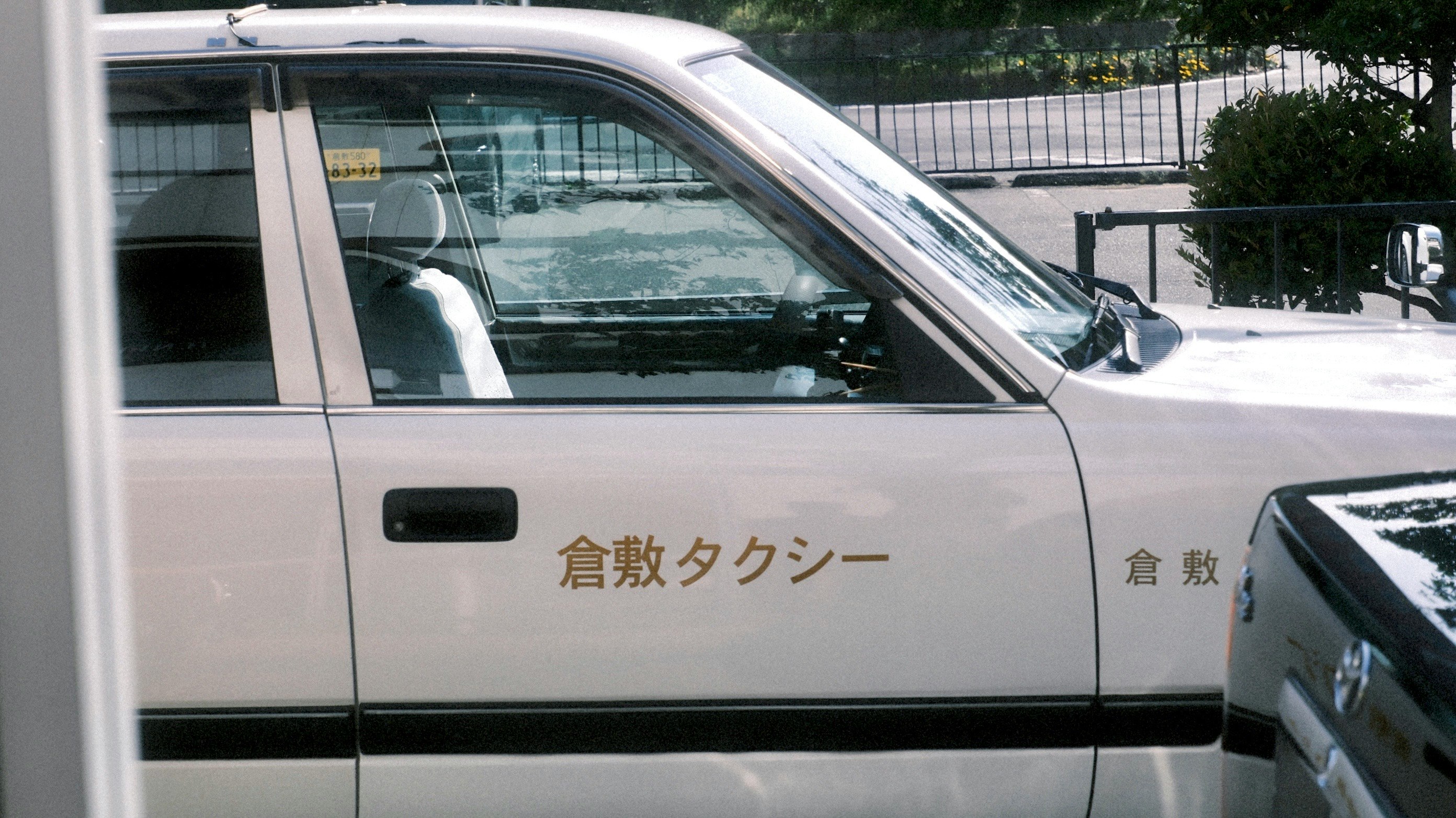 白い車の運転席側ドアに書かれた文字のあるタクシー