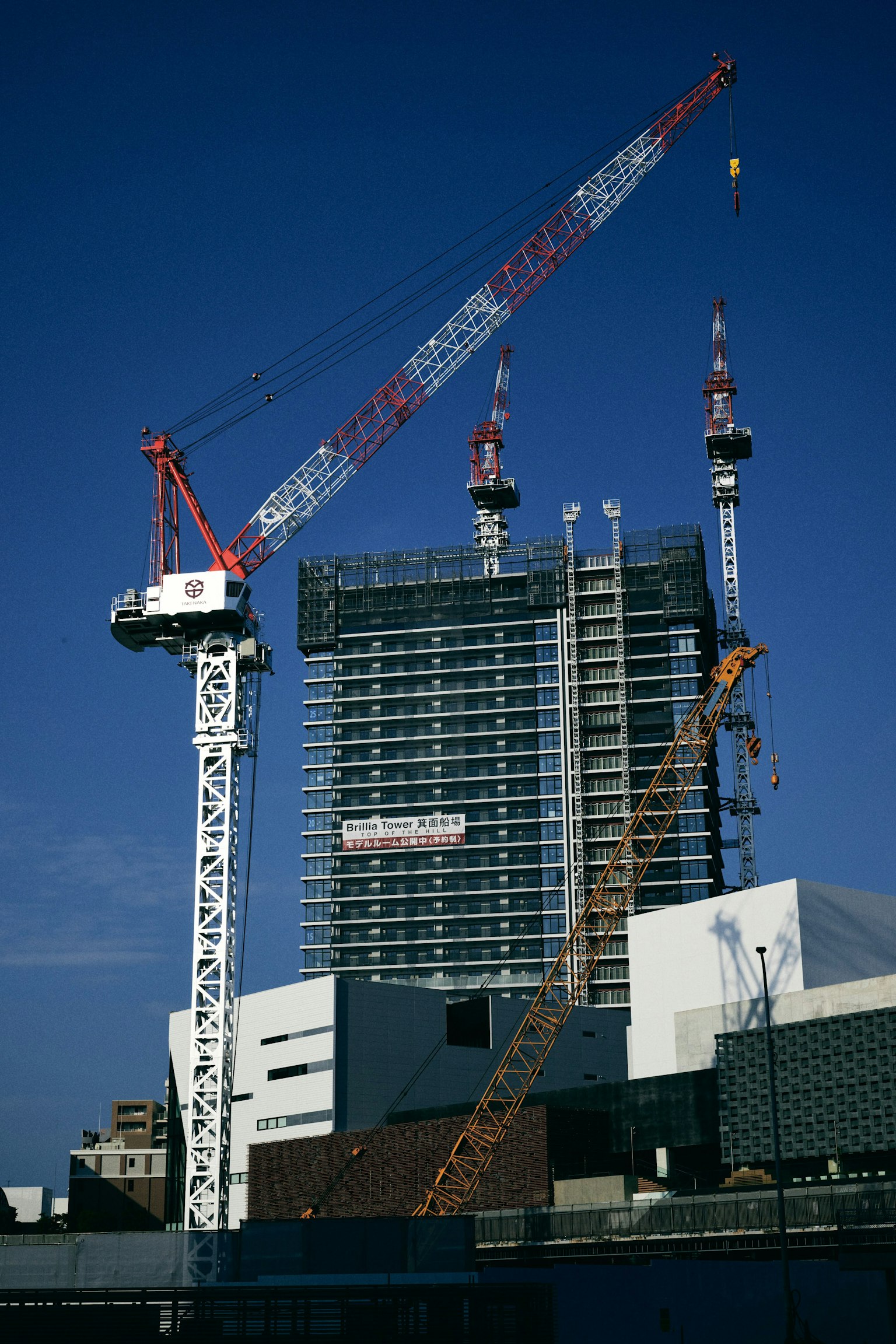 Situs konstruksi dengan beberapa crane dan gedung tinggi