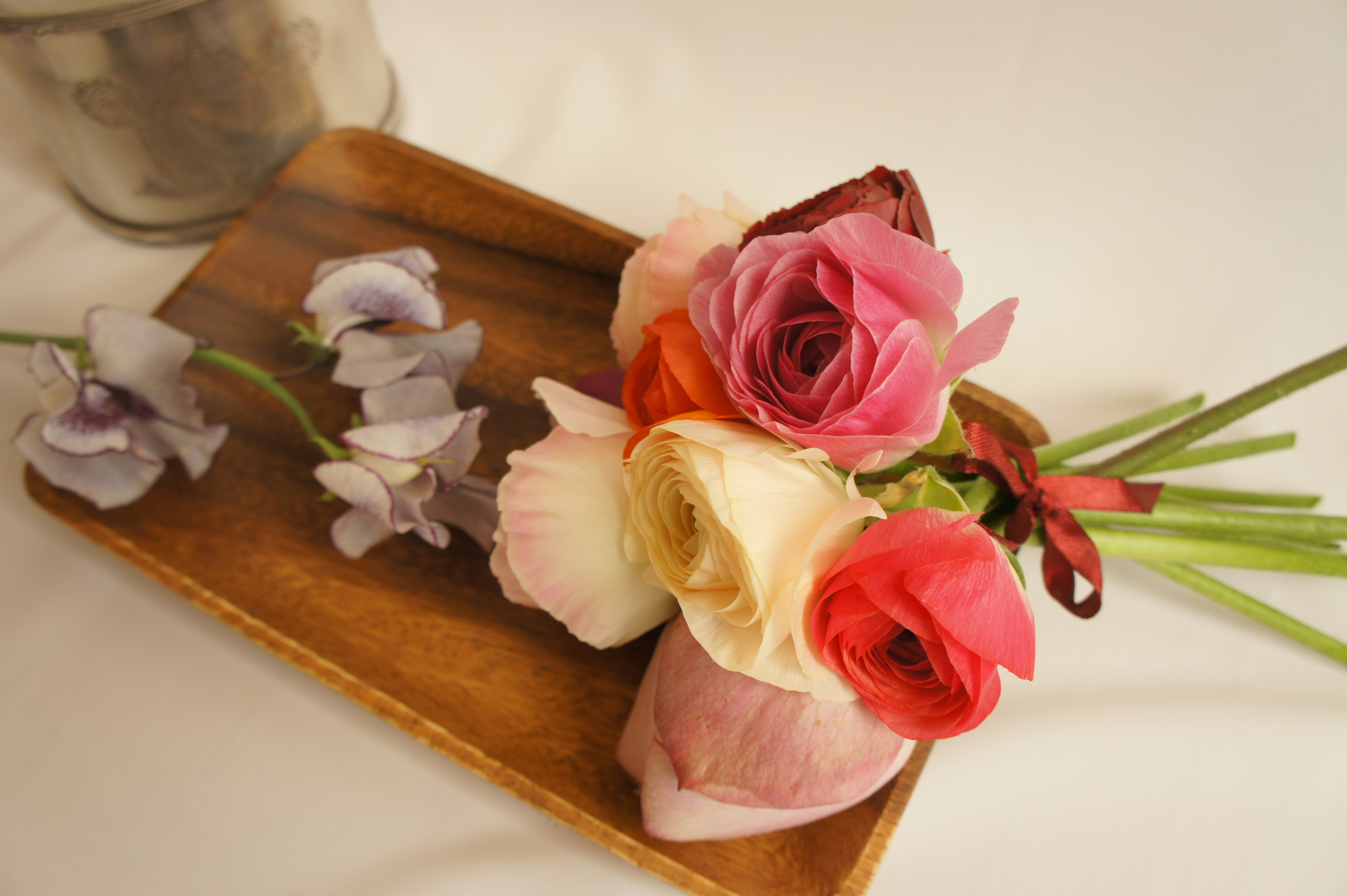 木の板の上に並ぶ花とバラの花束