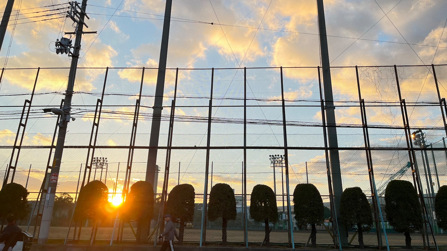Vista di un campo sportivo con il tramonto dietro la rete