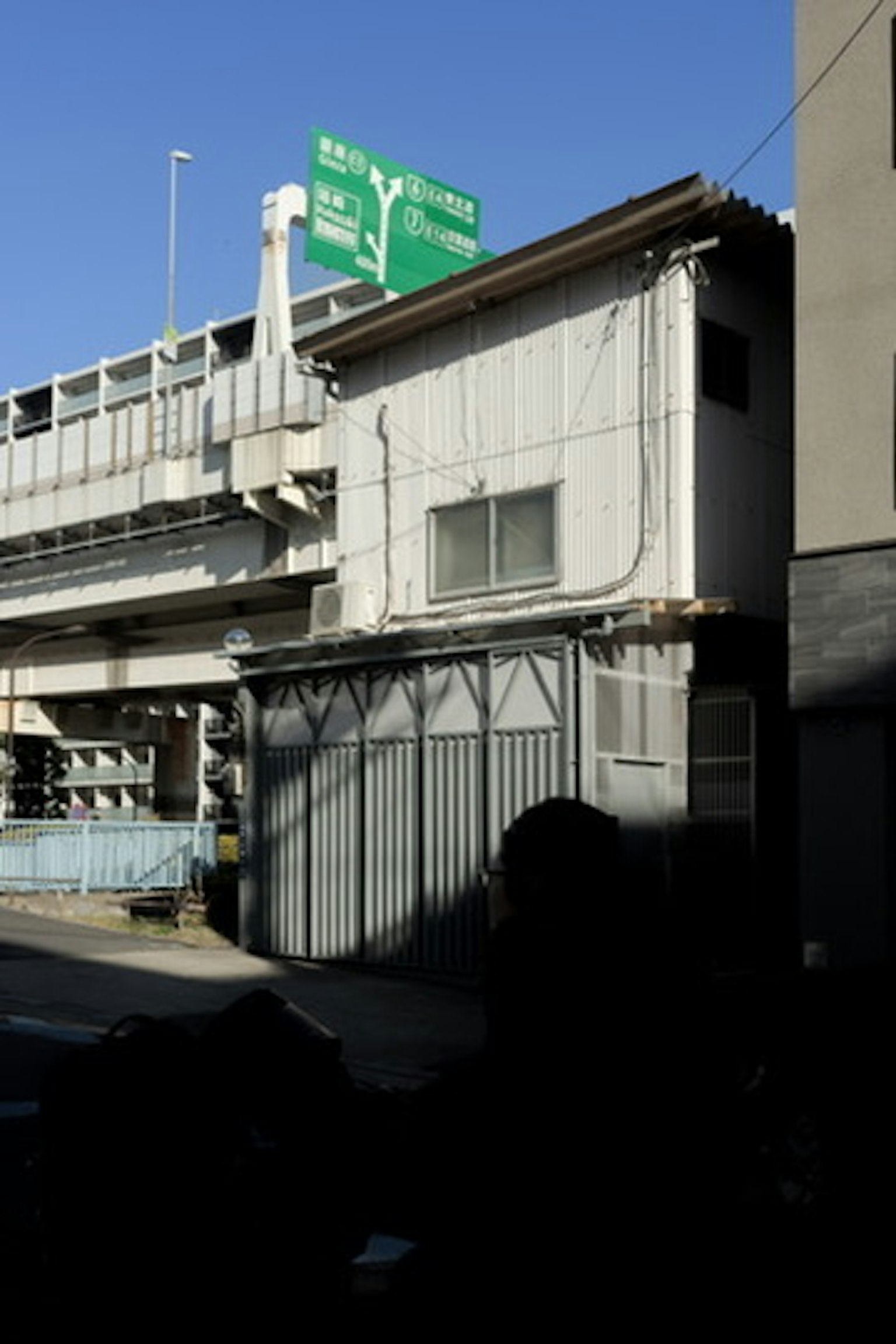 Edificio antiguo bajo un viaducto ferroviario con cielo azul claro