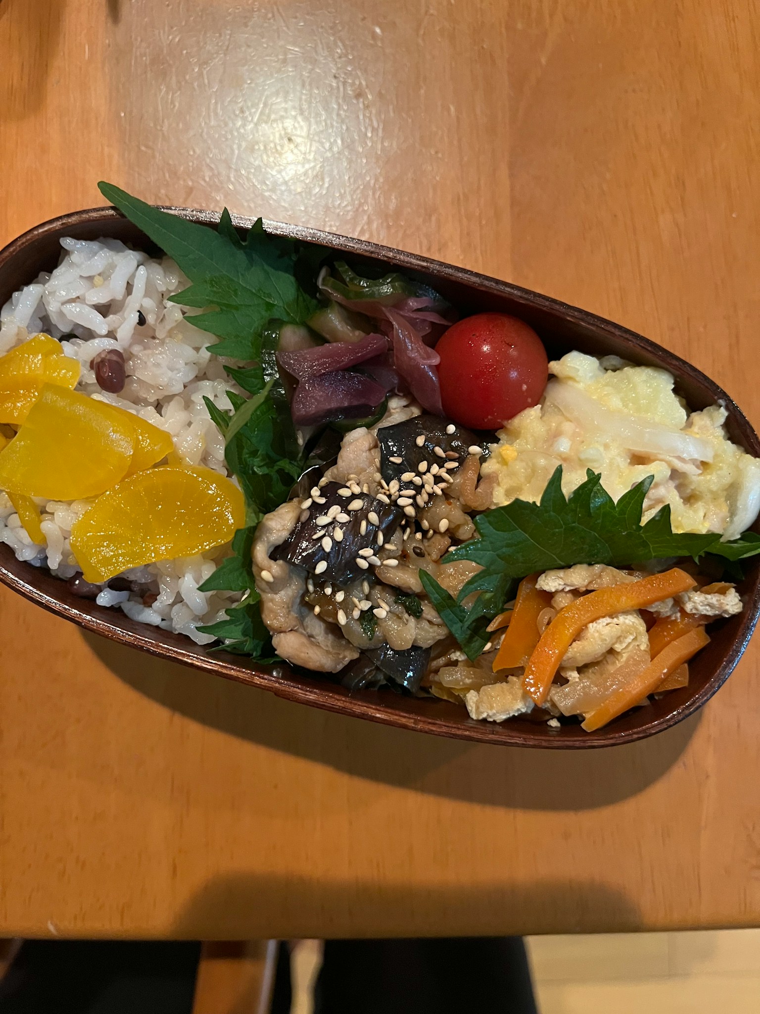 Hộp bento với cơm, gà, rau, trứng và lát cam
