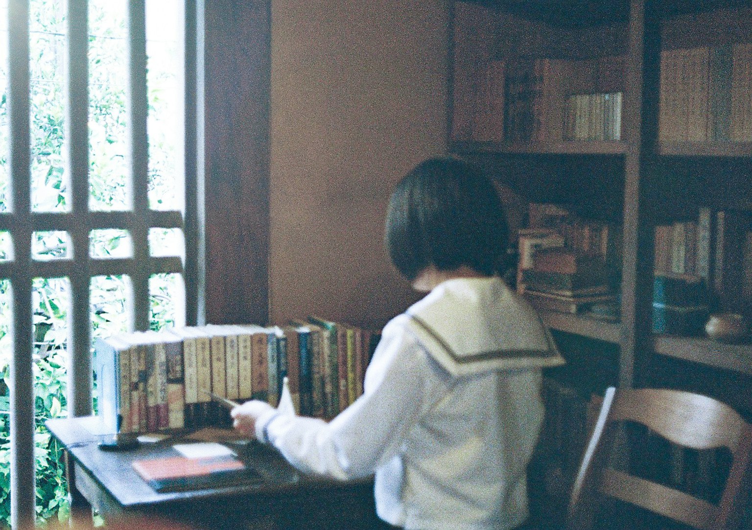 책장 앞에서 책을 정리하는 학생의 뒷모습