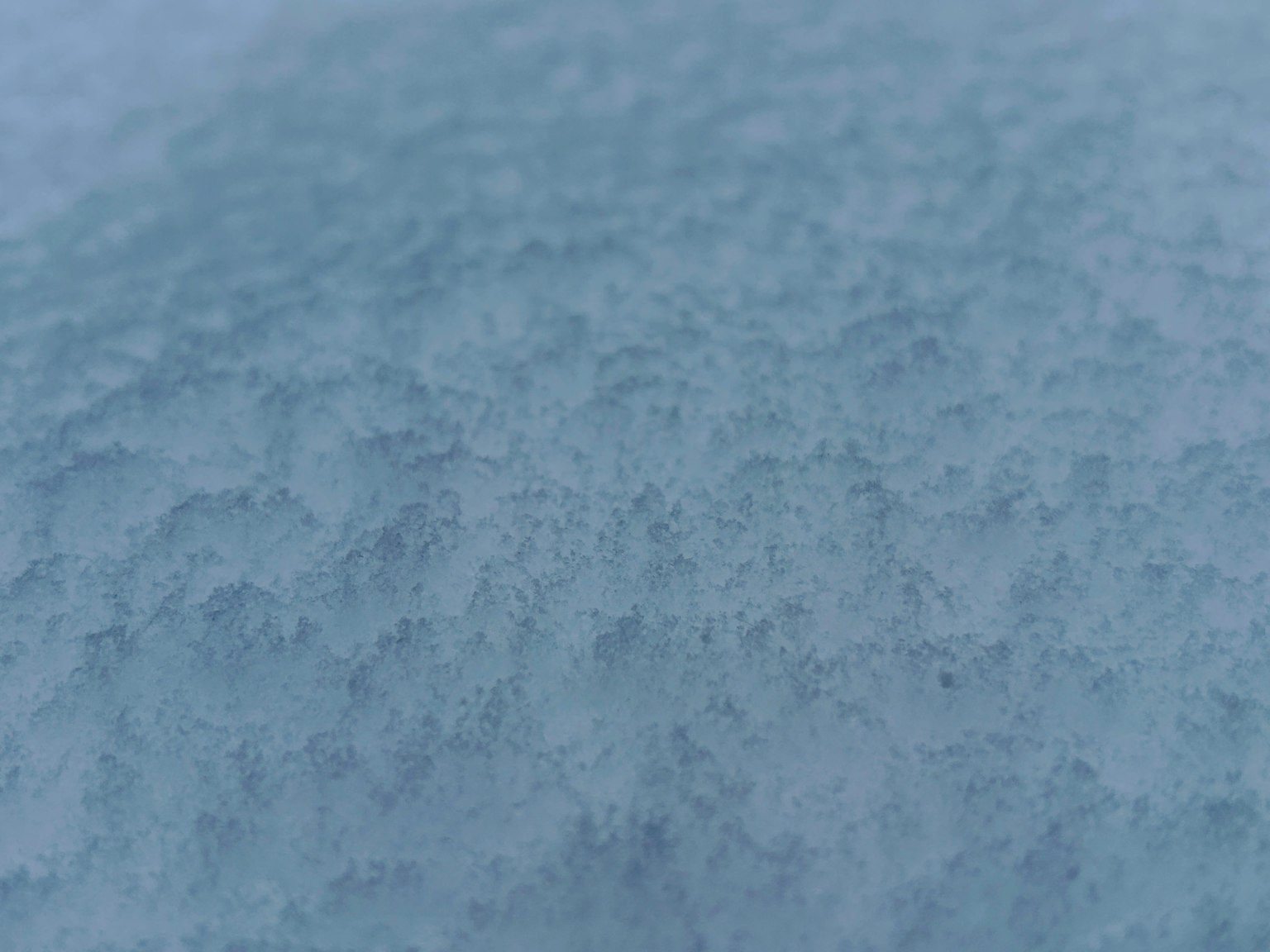 Close-up of textured snow surface with a cool blue tone