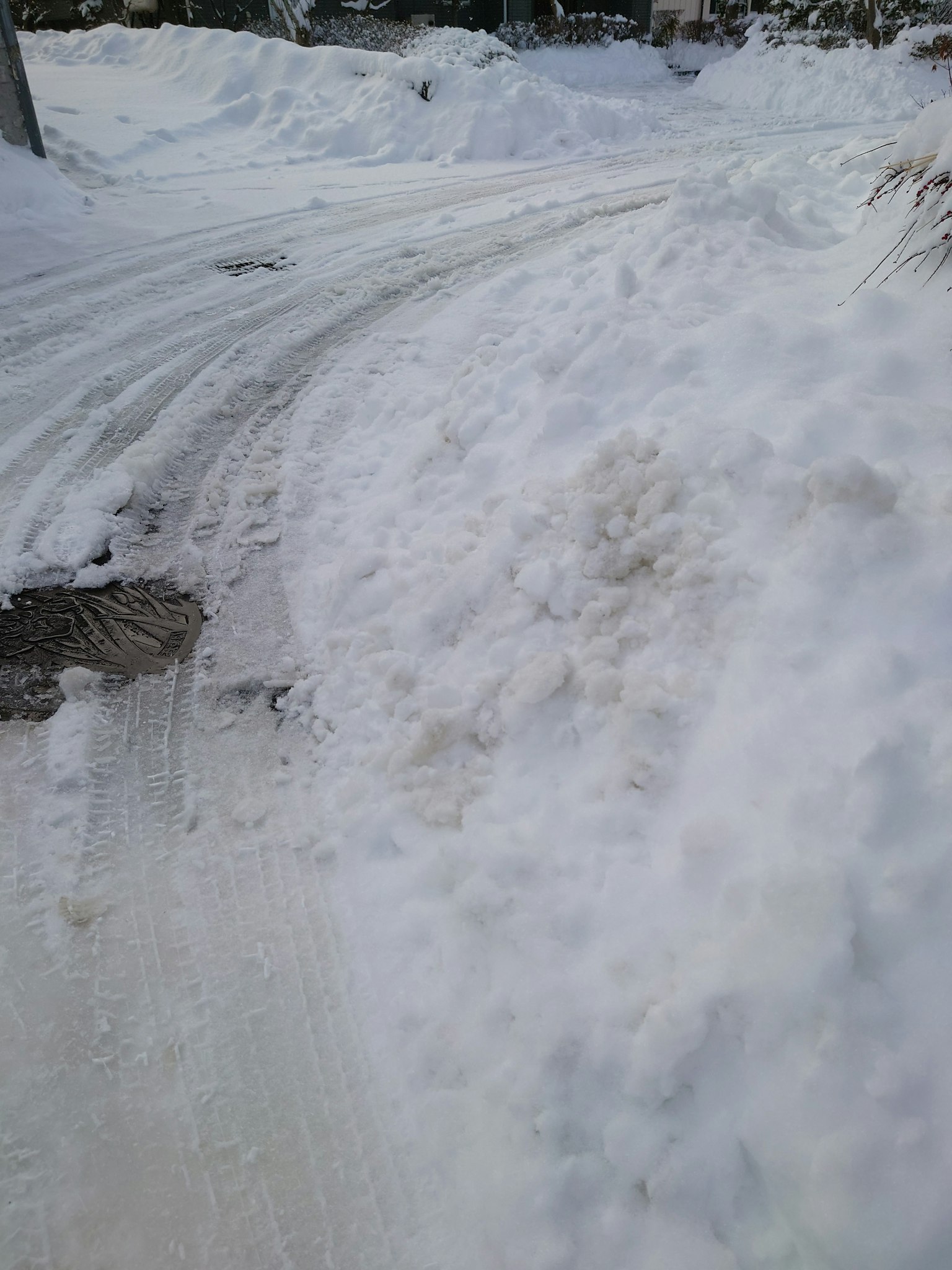 Schneebedeckte Straße mit Kurve und Reifenspuren