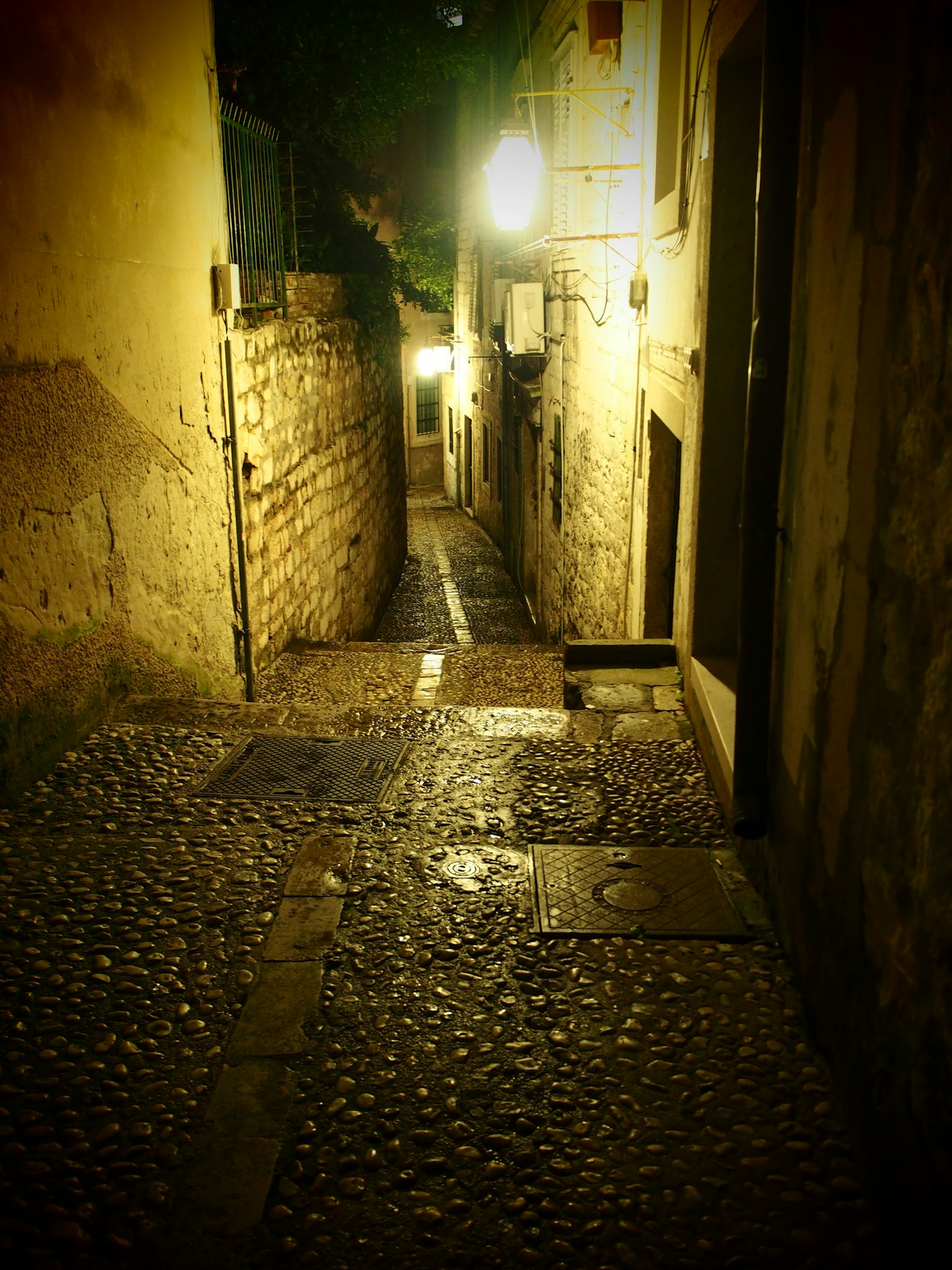 Rue étroite en pavés illuminée par des lampadaires la nuit