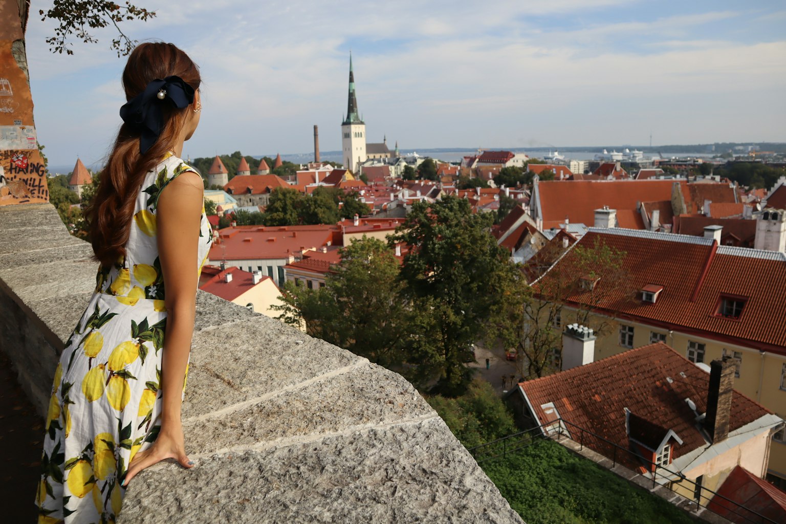 Donna in un vestito floreale giallo che guarda la città vecchia di Tallinn