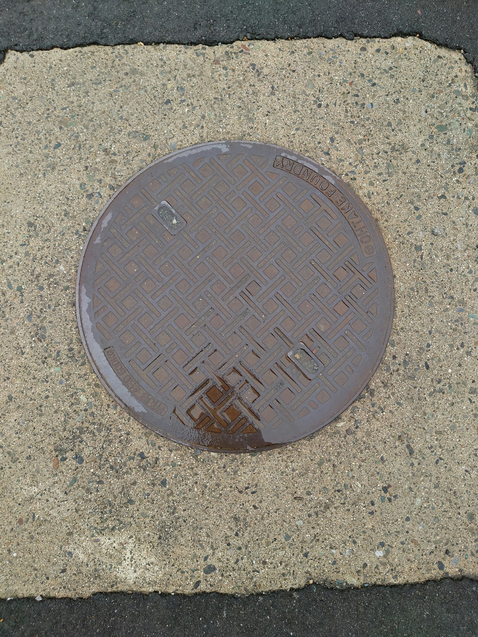 Runder Metallkanaldeckel auf einem Betonblock