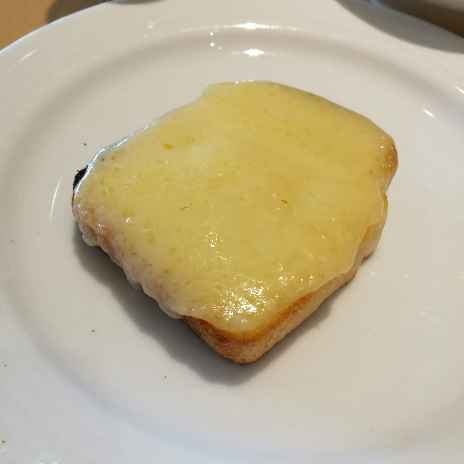 Roti bakar dengan keju leleh di atas piring putih
