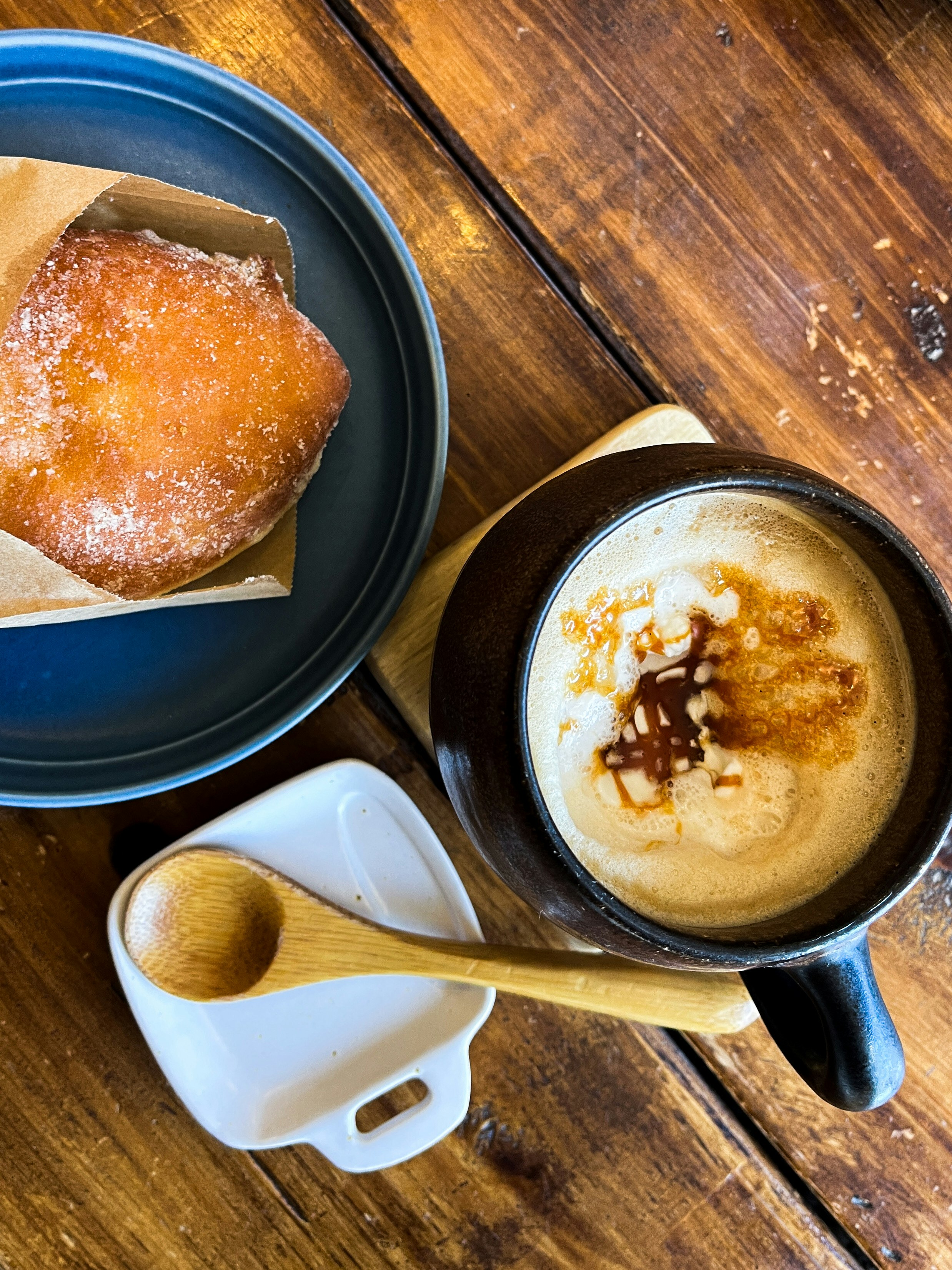 木目のテーブルに並ぶコーヒーとパンの朝食