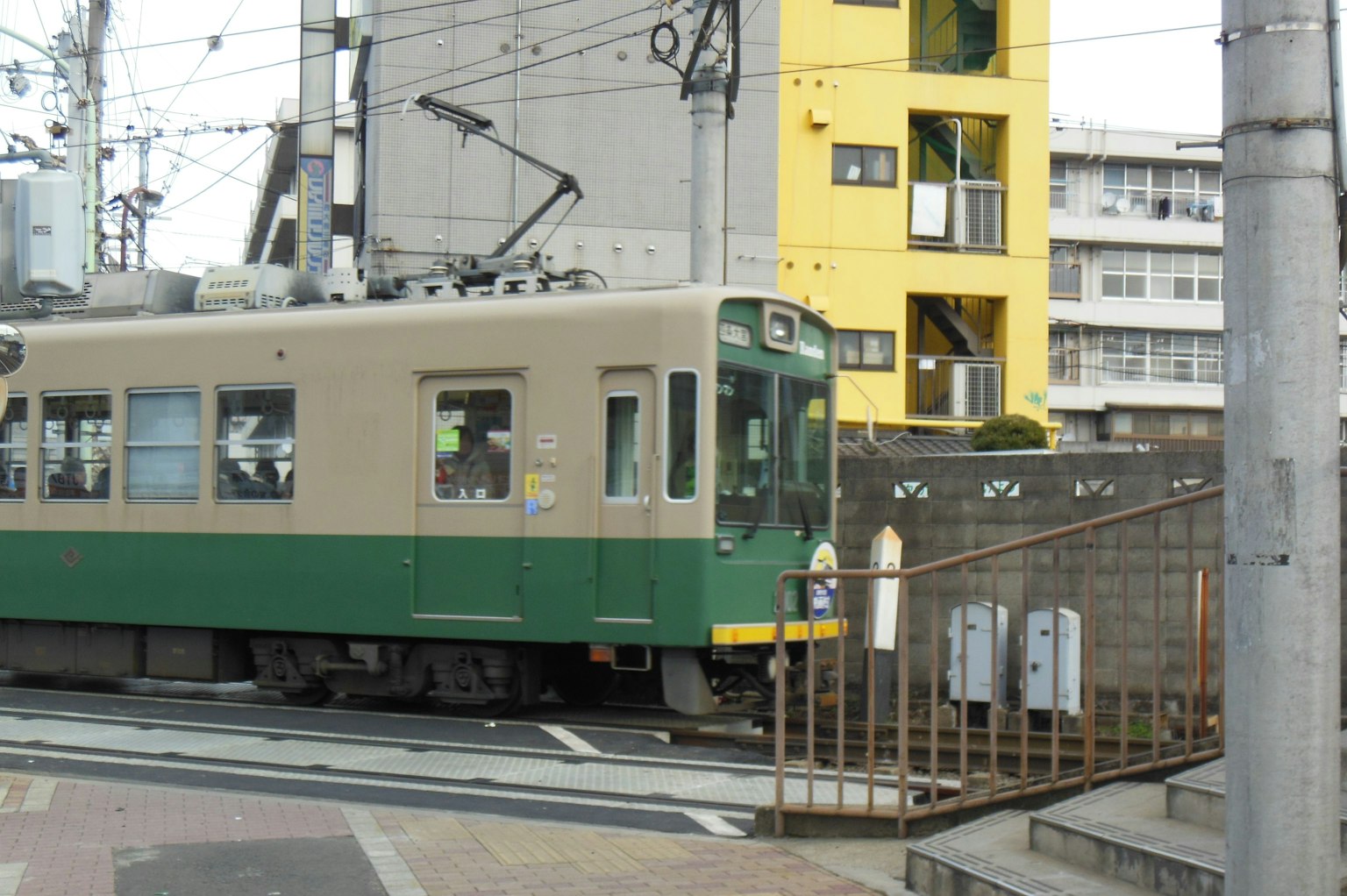 Un tram vert passant près d'un bâtiment jaune