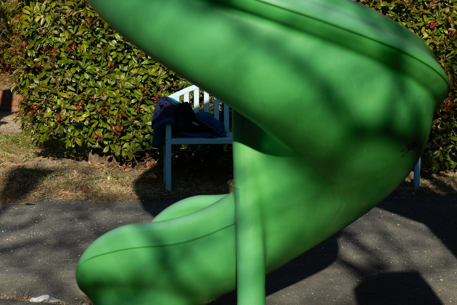 Grüne Rutsche in einem Park mit einem blauen Stuhl im Hintergrund