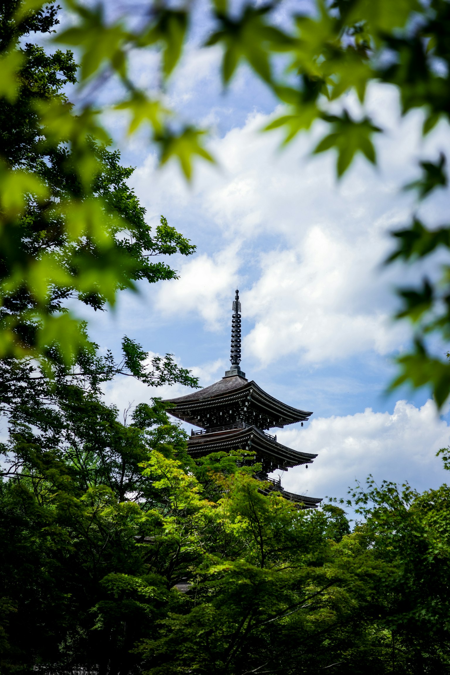 Fünfstöckige Pagode, die unter blauem Himmel von grünen Blättern umgeben ist