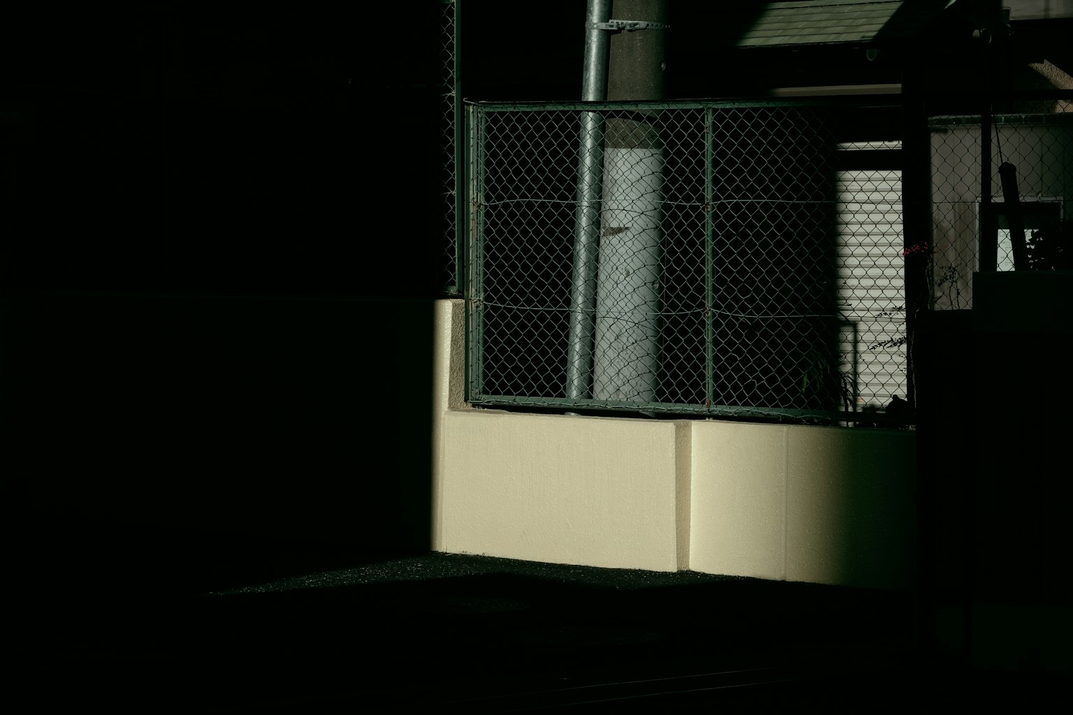 Hàng rào kim loại và tường trắng được bao quanh bởi nền tối