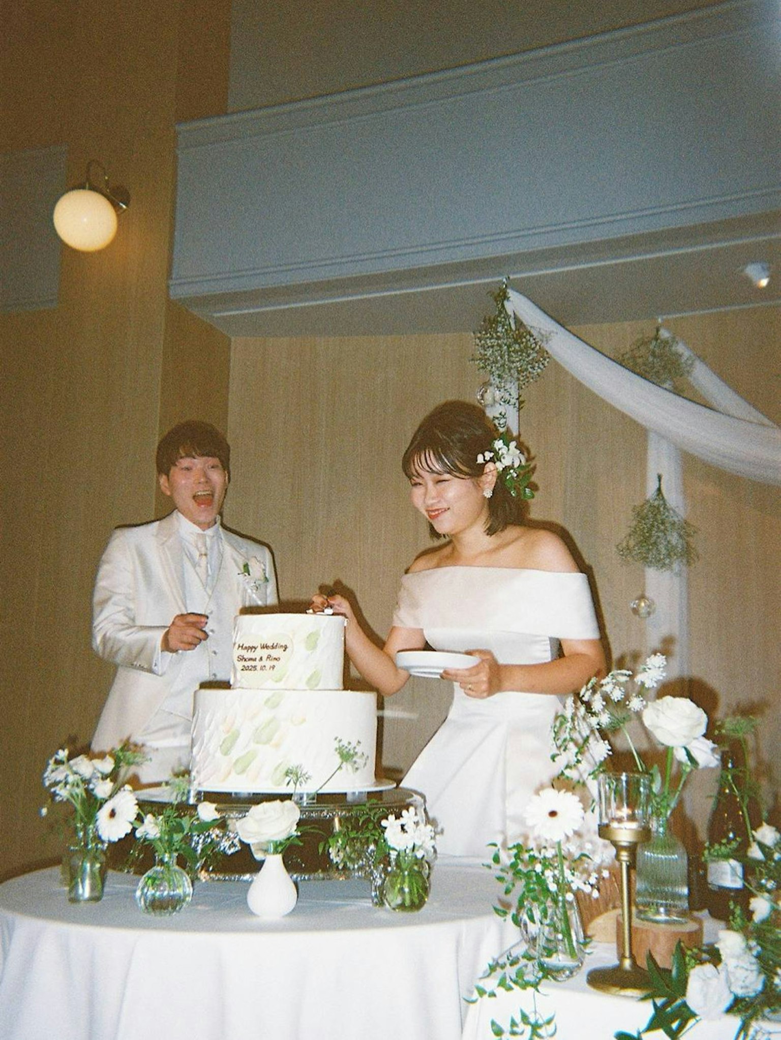 結婚式のケーキカットをする新婦と新郎の写真 白いドレスとタキシード 花と装飾が施されたテーブル