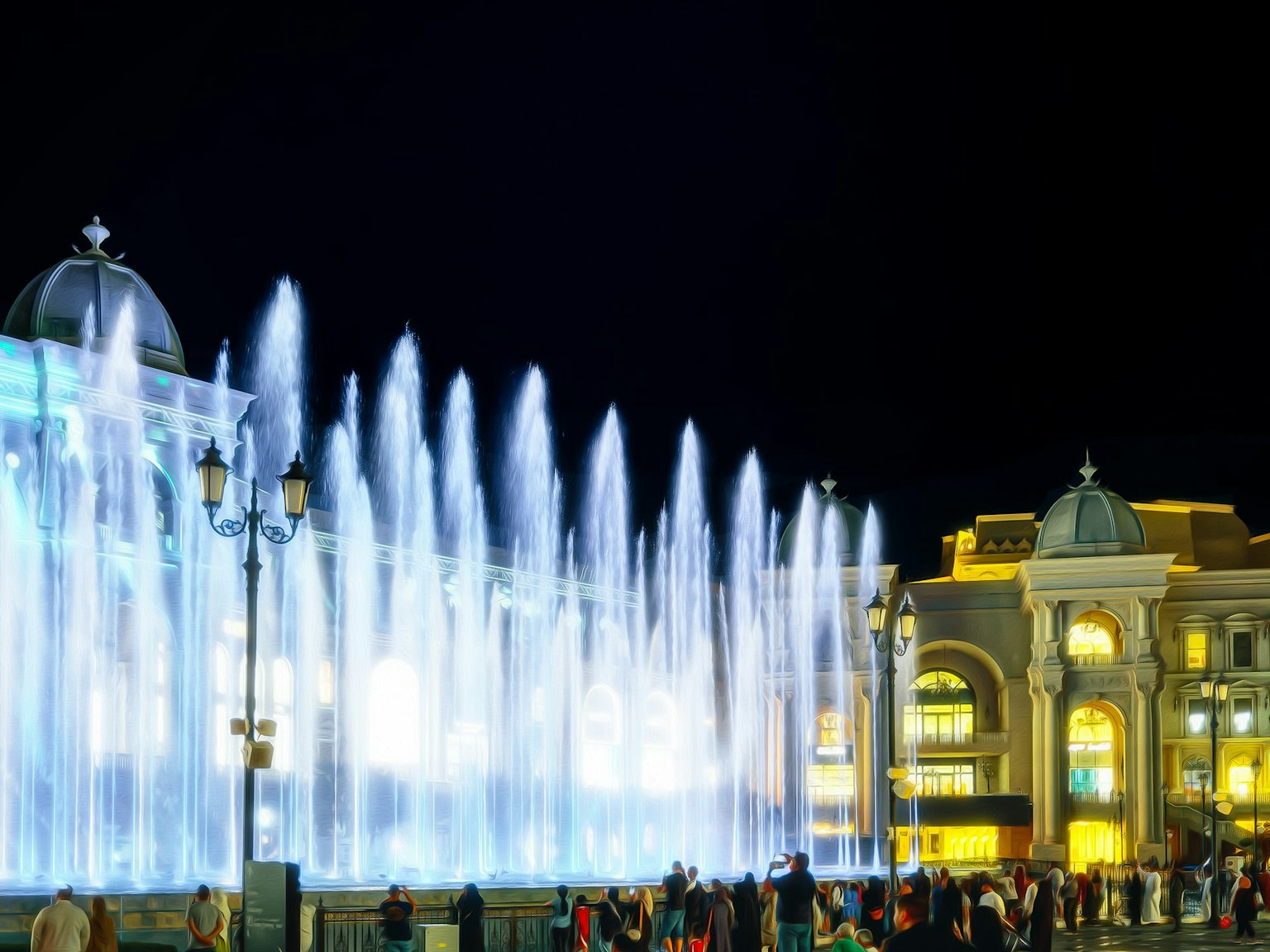 Espectáculo de fuentes nocturno vibrante con edificios iluminados
